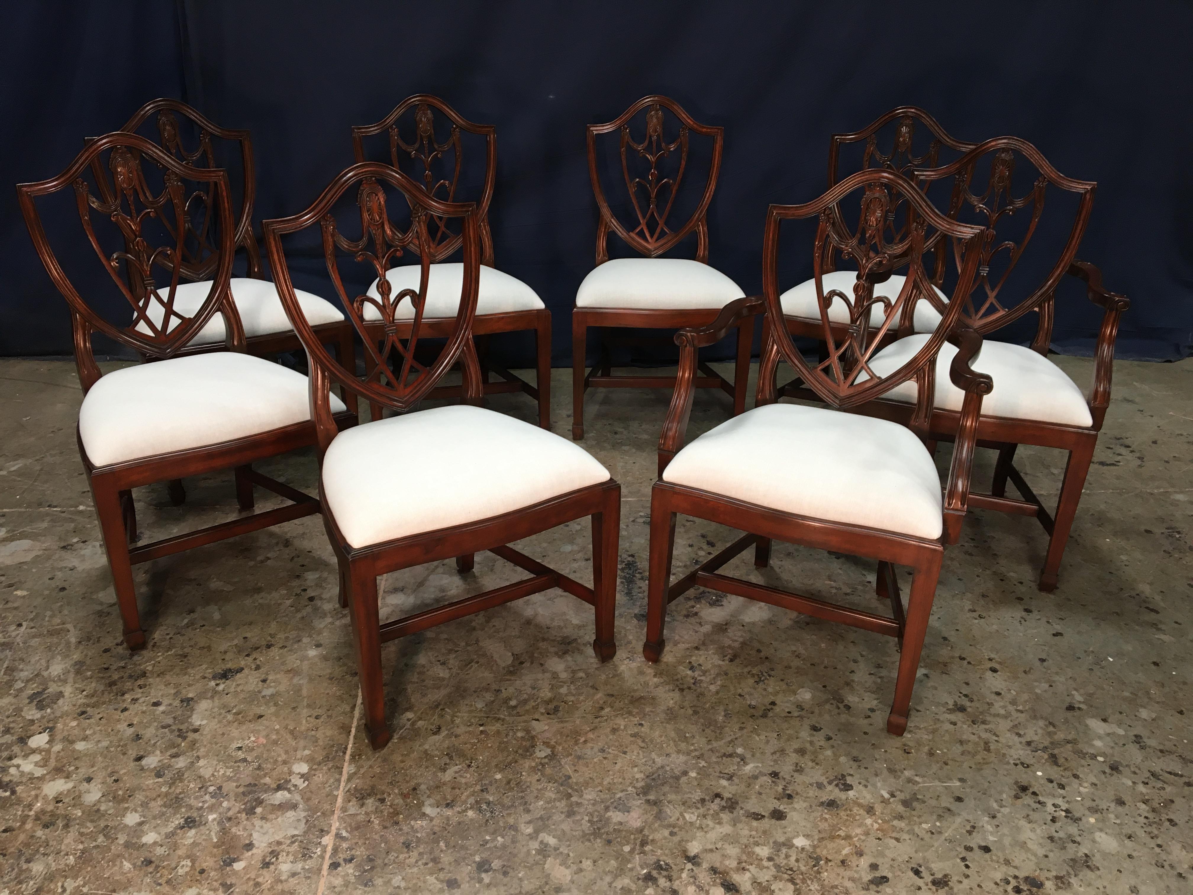 This is a set of eight (two arms and eight sides) mahogany Shieldback dining chairs by Leighton Hall. They feature the classic shieldback design with square tapered legs. They feature our standard medium brown mahogany color. The chairs come with a