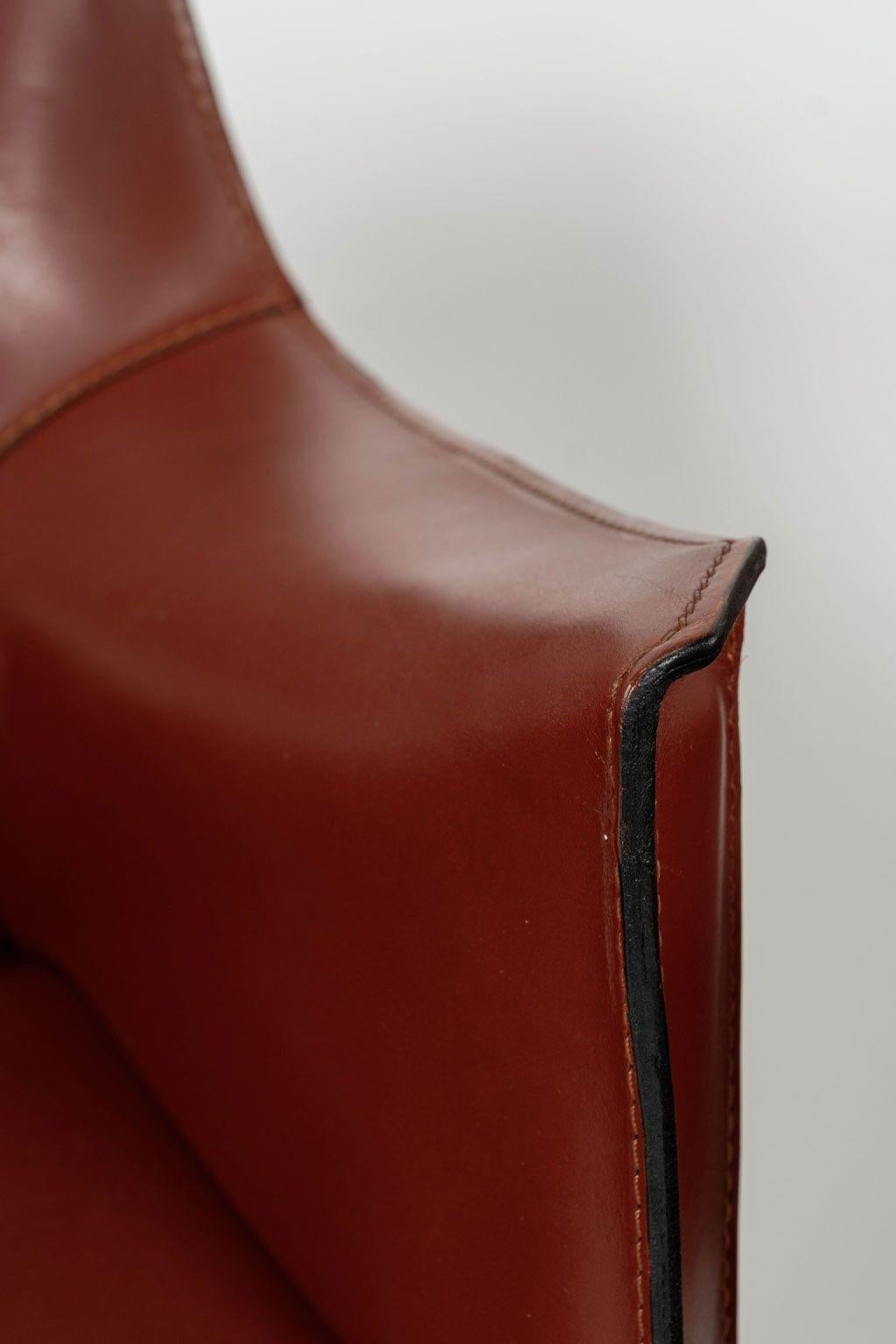 Eight Mario Bellini Cab 413 armchairs in rosso cina finish, fabricated by Cassina in the 1980s. Flexible steel frame covered with a skin of high quality saddle leather. This elegant, versatile chair is equally suitable for the dining room, study or