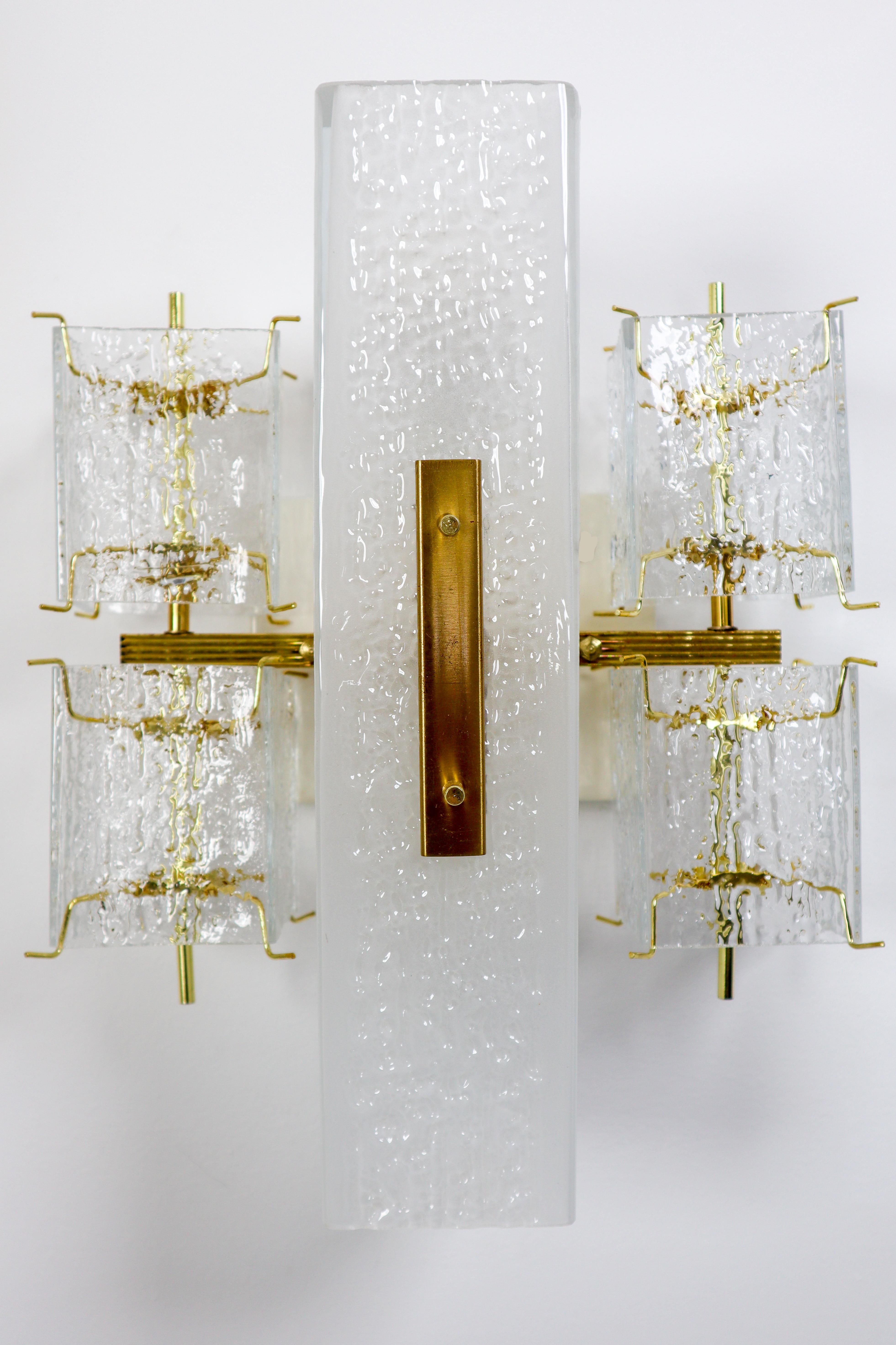 Midcentury wall lights, in glass and brass, Europe, 1970s. 

This elegant wall light features four small rectangular structured glass shades and a rectangular opaque central section. The frame is brass and holds small brass pins on which the square