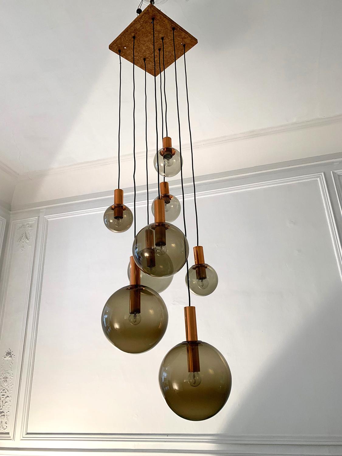 Beautiful ceiling lamp with 8 light points, produced by RAAK, 1970s. The ceiling lamp is made of a metal panel covered with cork from which hang 8 bright points in coppered metal finished with balls of smoked glass having different