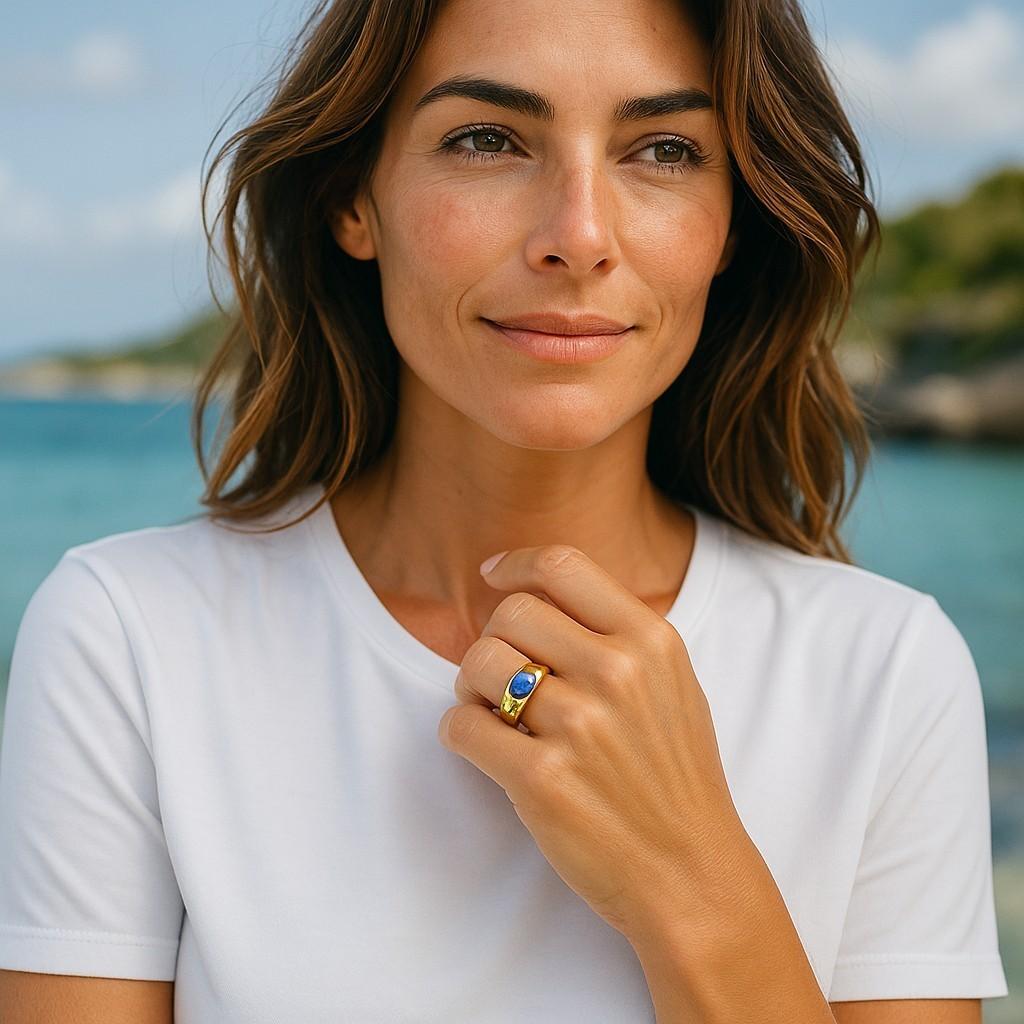 The Eighteen Karat Yellow Gold Ceylon Cabochon Sapphire and Diamond Ring is a stunning piece of jewelry that features a beautiful cabochon sapphire from Ceylon (now known as Sri Lanka), accented by small diamonds.
The sapphire is cut in a cabochon