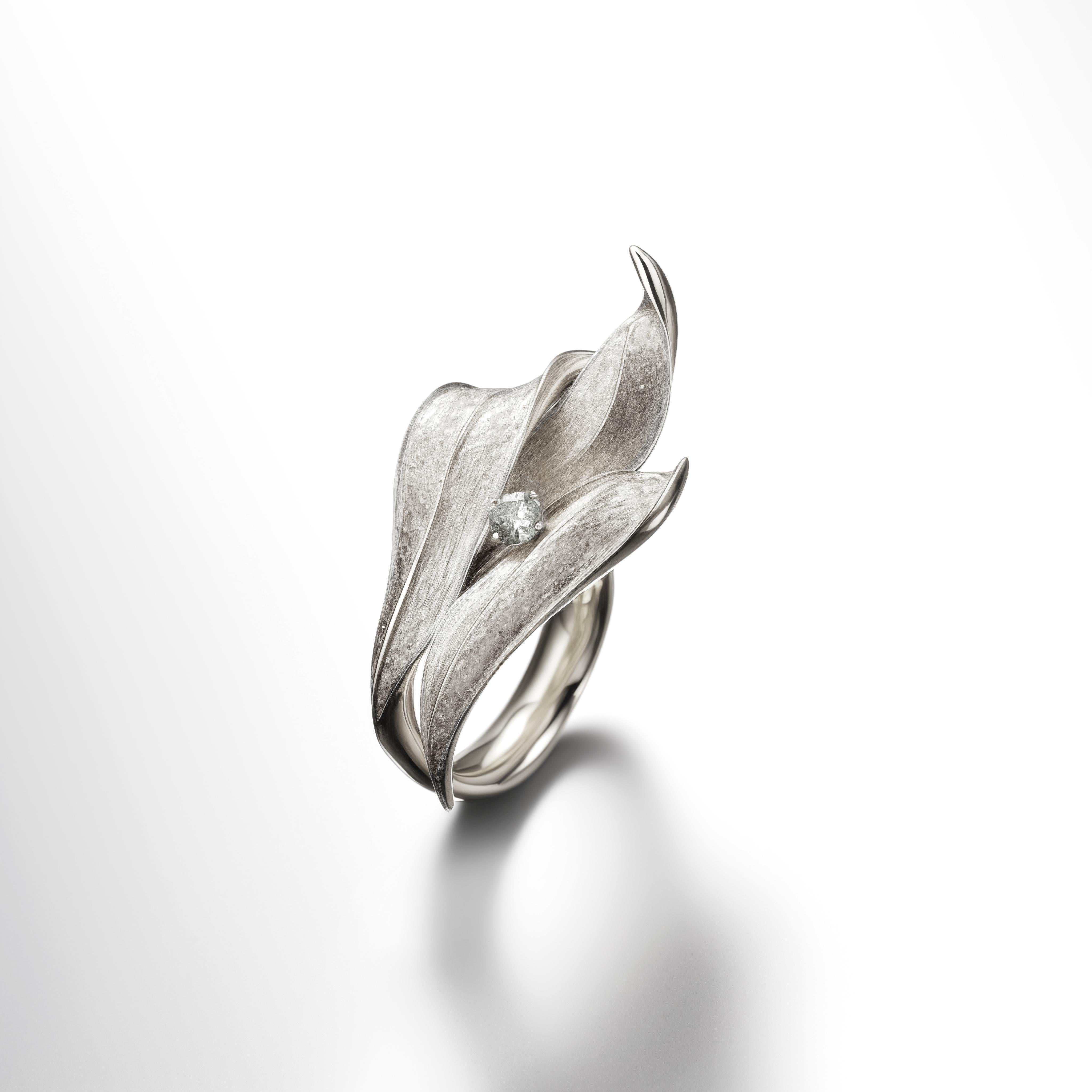 This contemporary Lily of The Valley Engagement Ring is made of 18 karat white gold and one round white sapphire. It has a sculptural shape. We work with German gems companies that have been in business since the 19th century. The ring can be