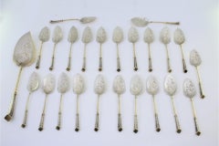 Eighteen silver ice cream scoops and shovel with gilt twists and engravings
