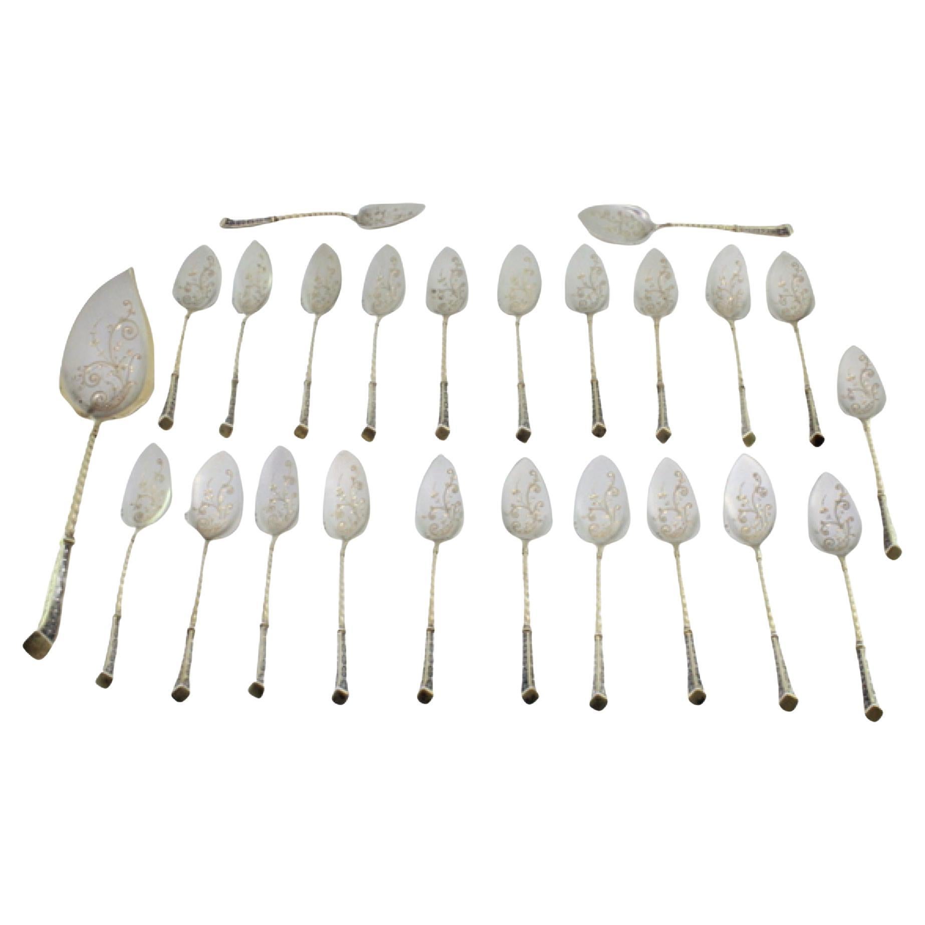 Eighteen silver ice cream scoops and shovel with gilt twists and engravings