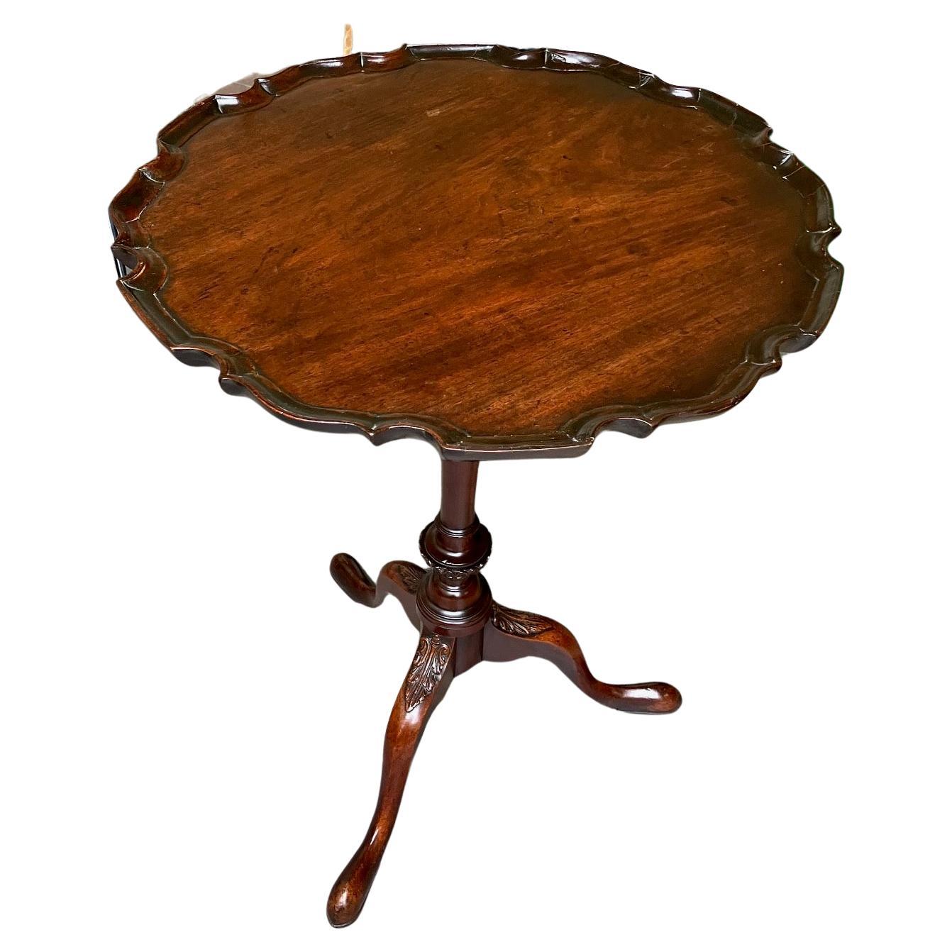 A good quality English mahogany candle stand or side table, the solid single board mahogany top with a carved pie crust edge, supported on an elegant ring turned standard with carved vasiform element supported on a tripod base with acnthus carved