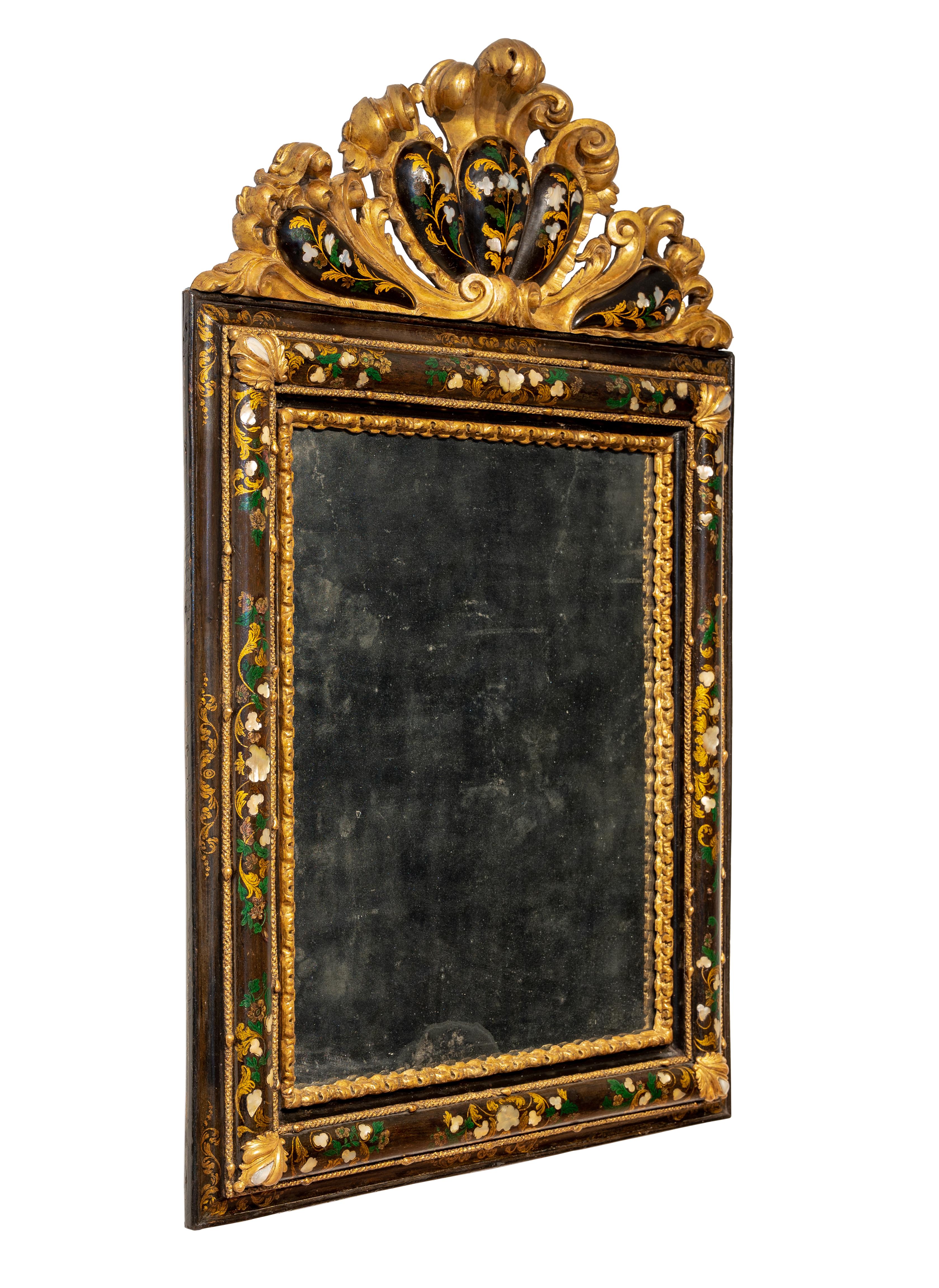 Extraordinary venetian mirror in carved, lacquered and gilded wood. Slightly rounded band with foliate decorations in polychrome lacquer and mother-of-pearl inlays, carved and foliated friezes at the corners, shaped, rounded cymatium, also gilded