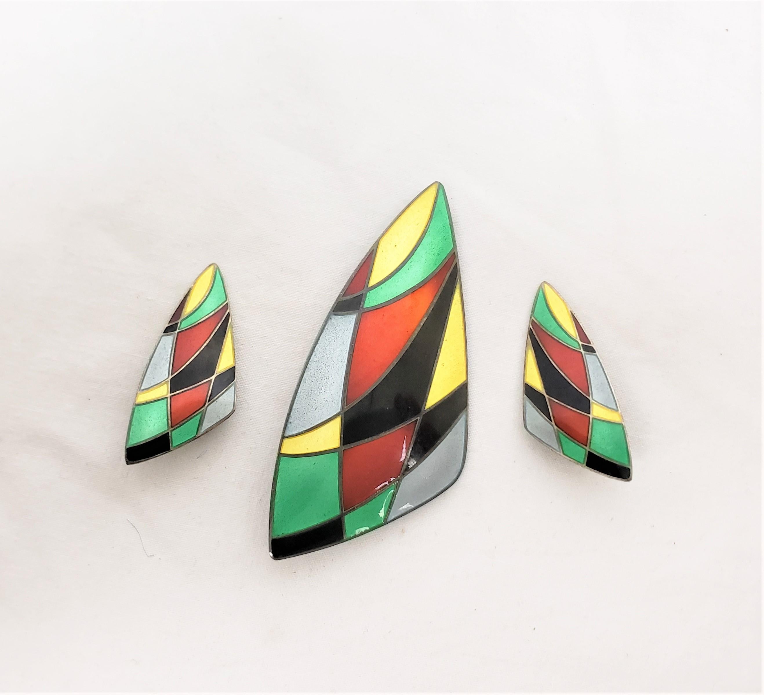 Dieses Set aus Brosche und Ohrringen wurde um 1960 von Eigil Jensen für Anton Michelsen aus Dänemark im Stil der Jahrhundertmitte entworfen. Das Set besteht aus Sterlingsilber und hat eine stilisierte Boots- oder Dreiecksform mit leuchtenden