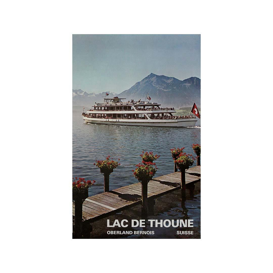 This original circa 1960 travel poster, created by the artist Eigstler, invites viewers to discover the tranquil beauty of Lake Thun (Lac de Thoune), located in the heart of the Oberland Bernois region of Switzerland. Commissioned during the golden