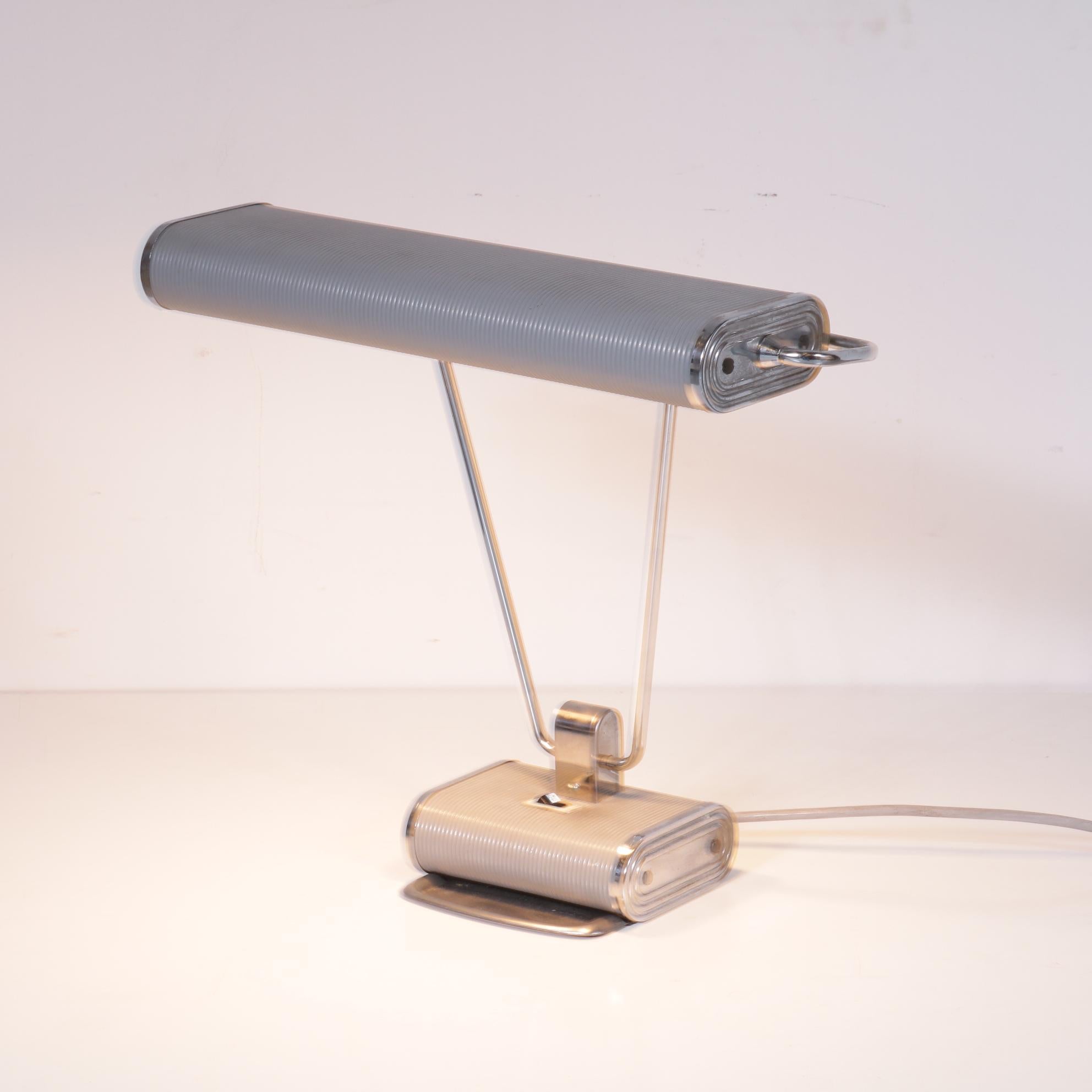Beautiful desk lamp designed by Eileen Gray, manufactured by Jumo in France, circa 1940.

This eye-catching Art Deco lamp is made of beautiful quality grey and chrome plated metal. The hood and foot has a ribbed finish, which creates a luxurious