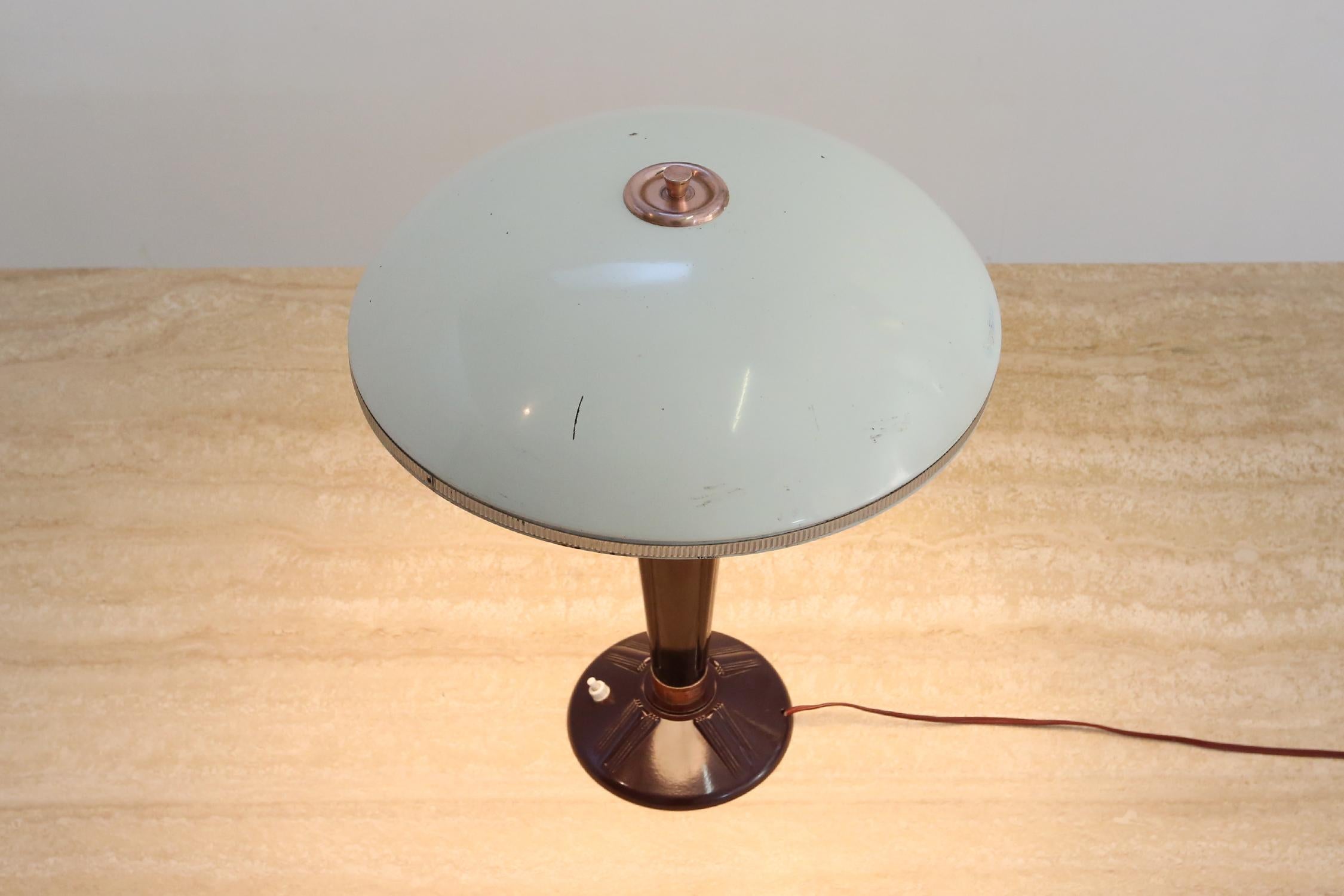 Lampe de table Art Deco par Eileen Gray conçue pour la compagnie française Jumo Ca.1940.
La lampe est composée d'une base en bakélite, d'un abat-jour émaillé blanc et de quelques détails en cuivre rouge.
La lampe est dans un état original avec