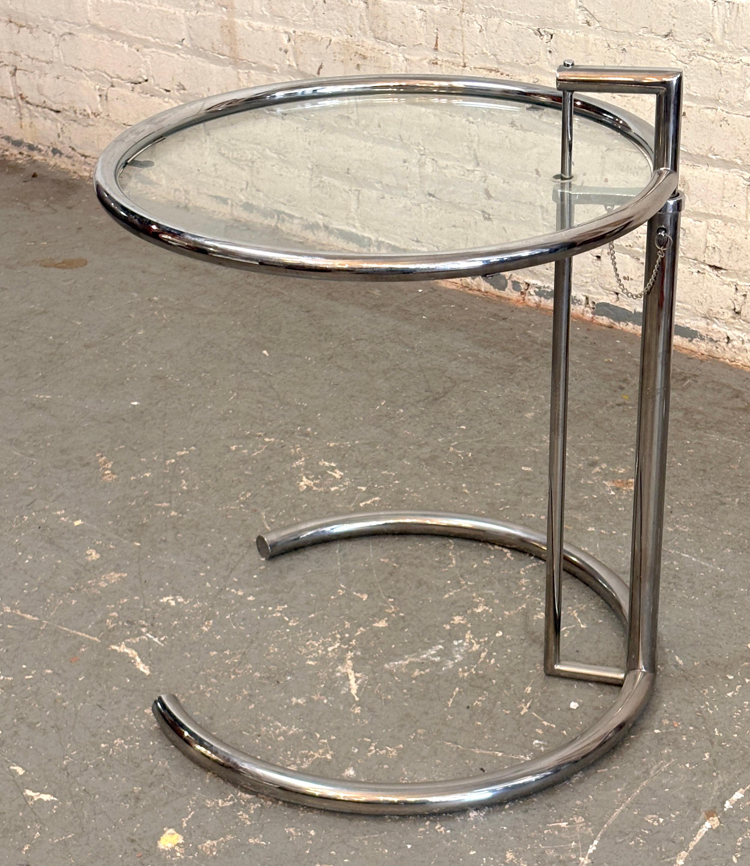 Ce classique de la modernité du milieu du siècle a été conçu par Eileen Gray en 1927 et reste un standard pour les maisons modernes. Le cadre tubulaire chromé supporte une table ronde en verre. La hauteur peut être réglée de 24,5 à 40