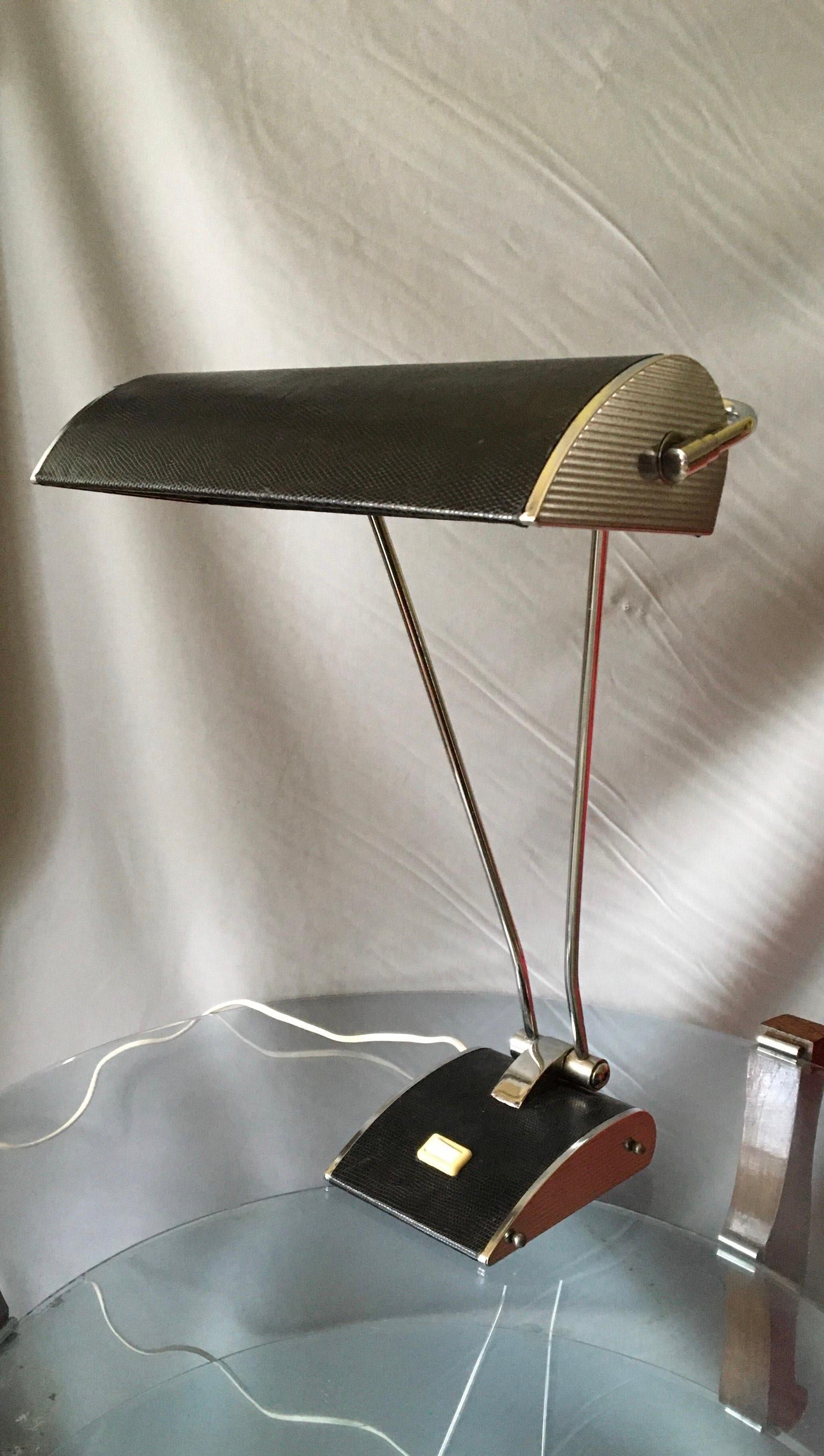 Très élégante lampe de table française des années 50, design/One, en métal chromé de style aviation et recouverte de lézard.
Le réflecteur peut se plier et pivoter pour un éclairage optimal.
La lampe est en excellent état, les parties électriques