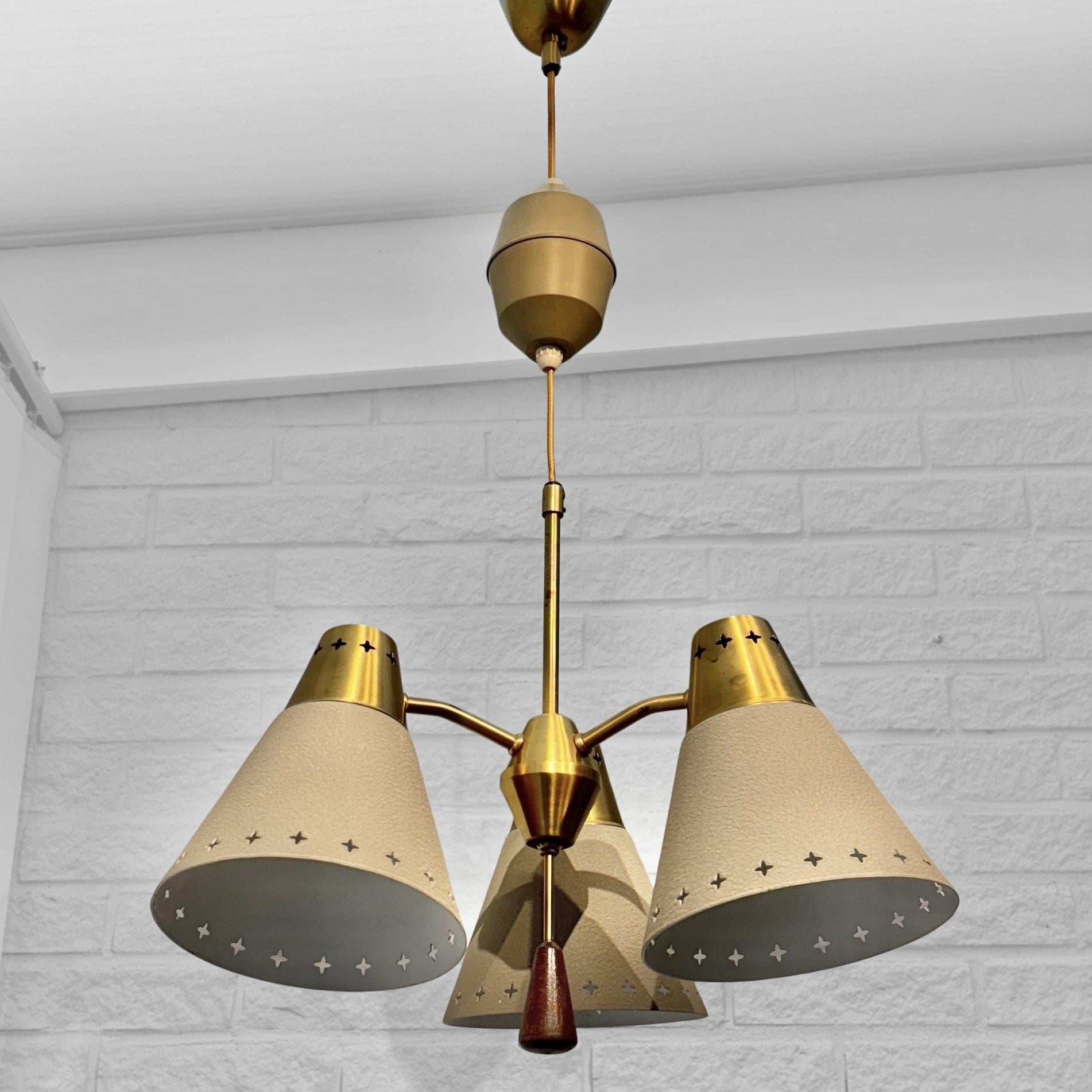 Una straordinaria lampada a sospensione della metà del secolo scorso, prodotta dal rinomato produttore svedese Einar Bäckströms Metallvarufabrik negli anni Cinquanta. Presenta tre bracci curvi in ottone che sorreggono paralumi conici in metallo,