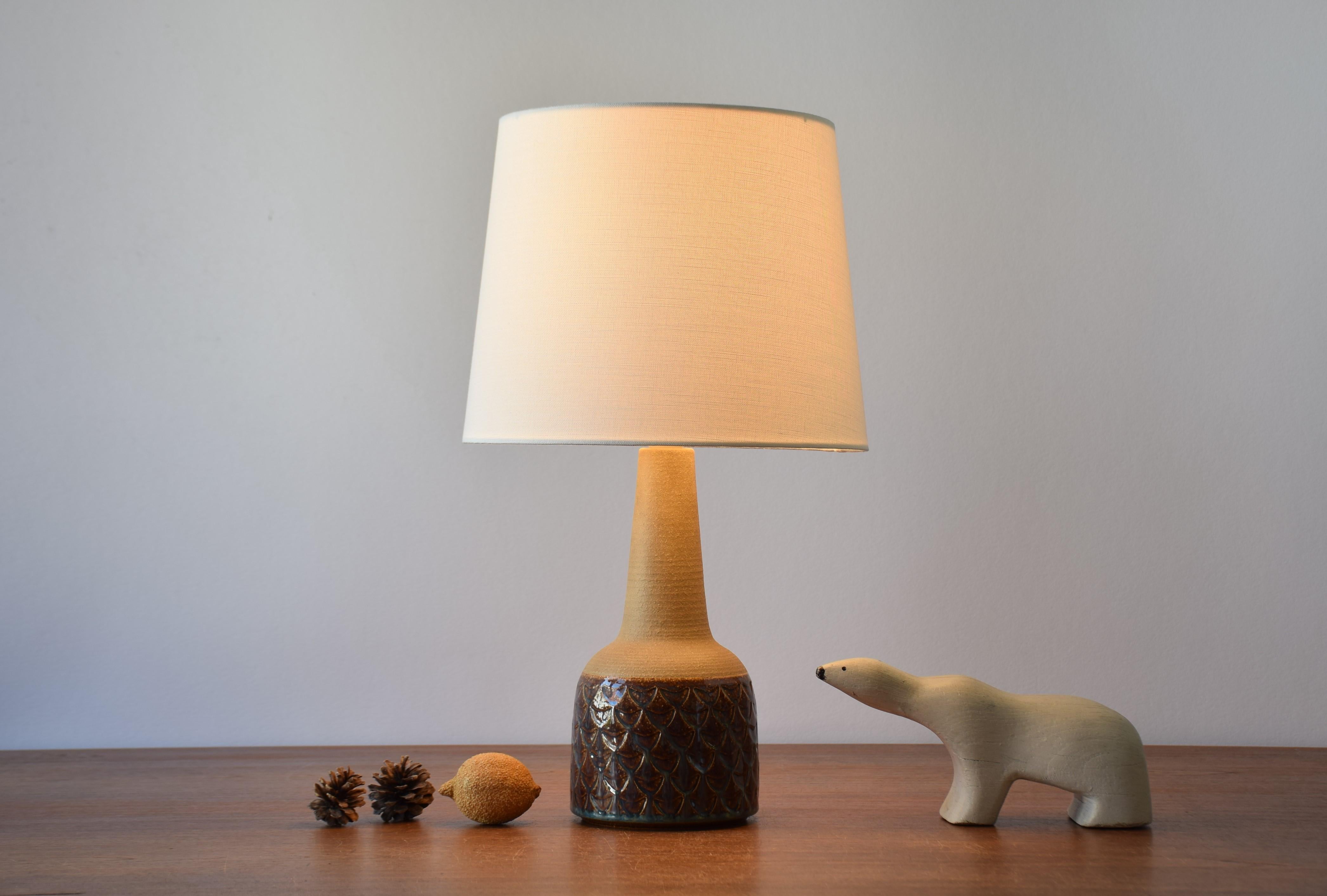 Table lamp by Einar Johansen for Søholm Stentøj, Denmark, circa 1960s.
The neck is unglazed and shows the warm sand colored glaze. The body is decorated with an embossed fish scales covered by shiny glaze in brown with blue elements.

Included is