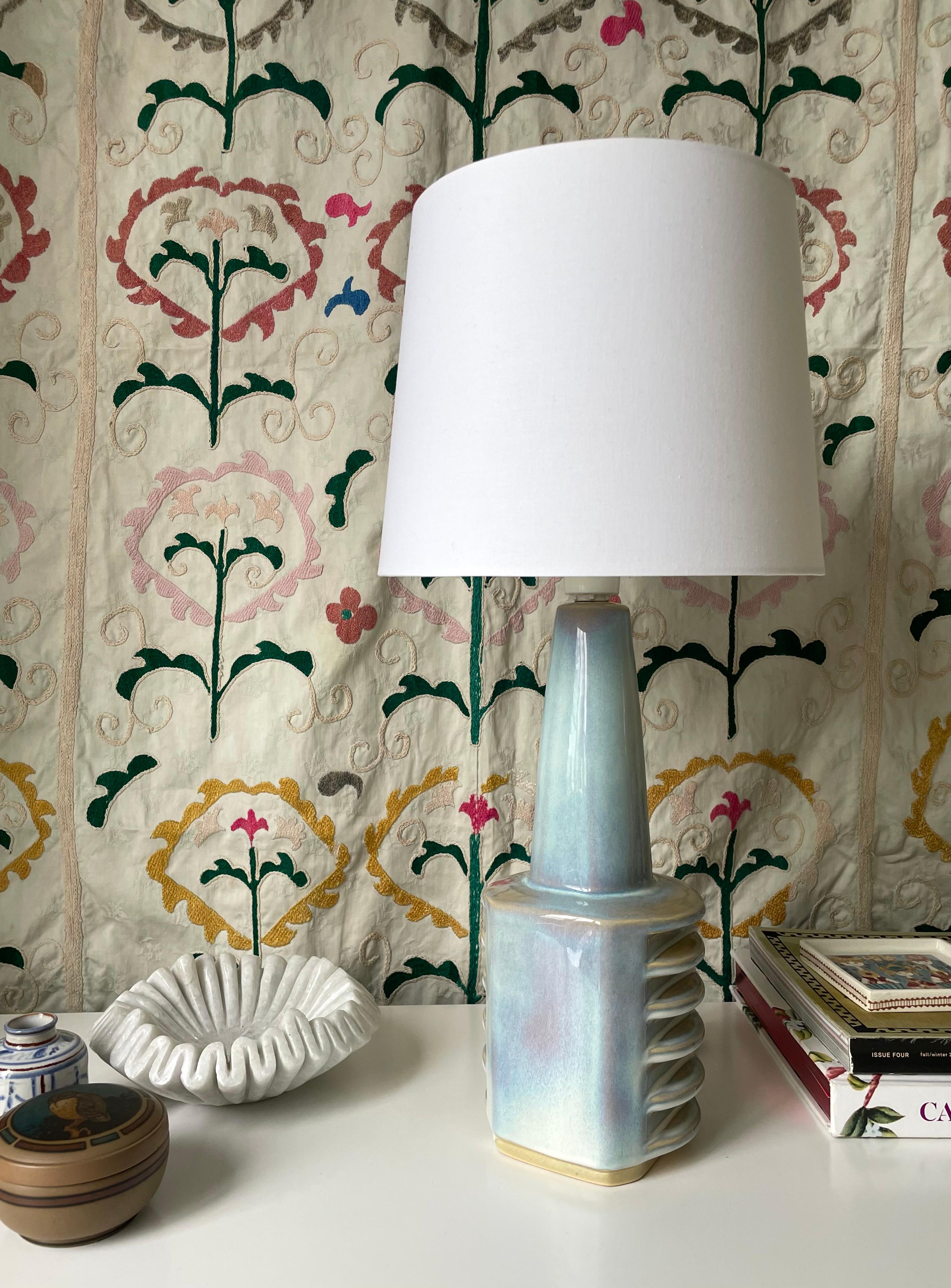Danish Mid-Century Modern stoneware table lamp by Einar Johansen for Søholm. Light blue shiny glaze mixed with lilac, caramel brown and white. Tall neck on sculptural base with rounded protruding discs on each side of the lamp. Rewired with original