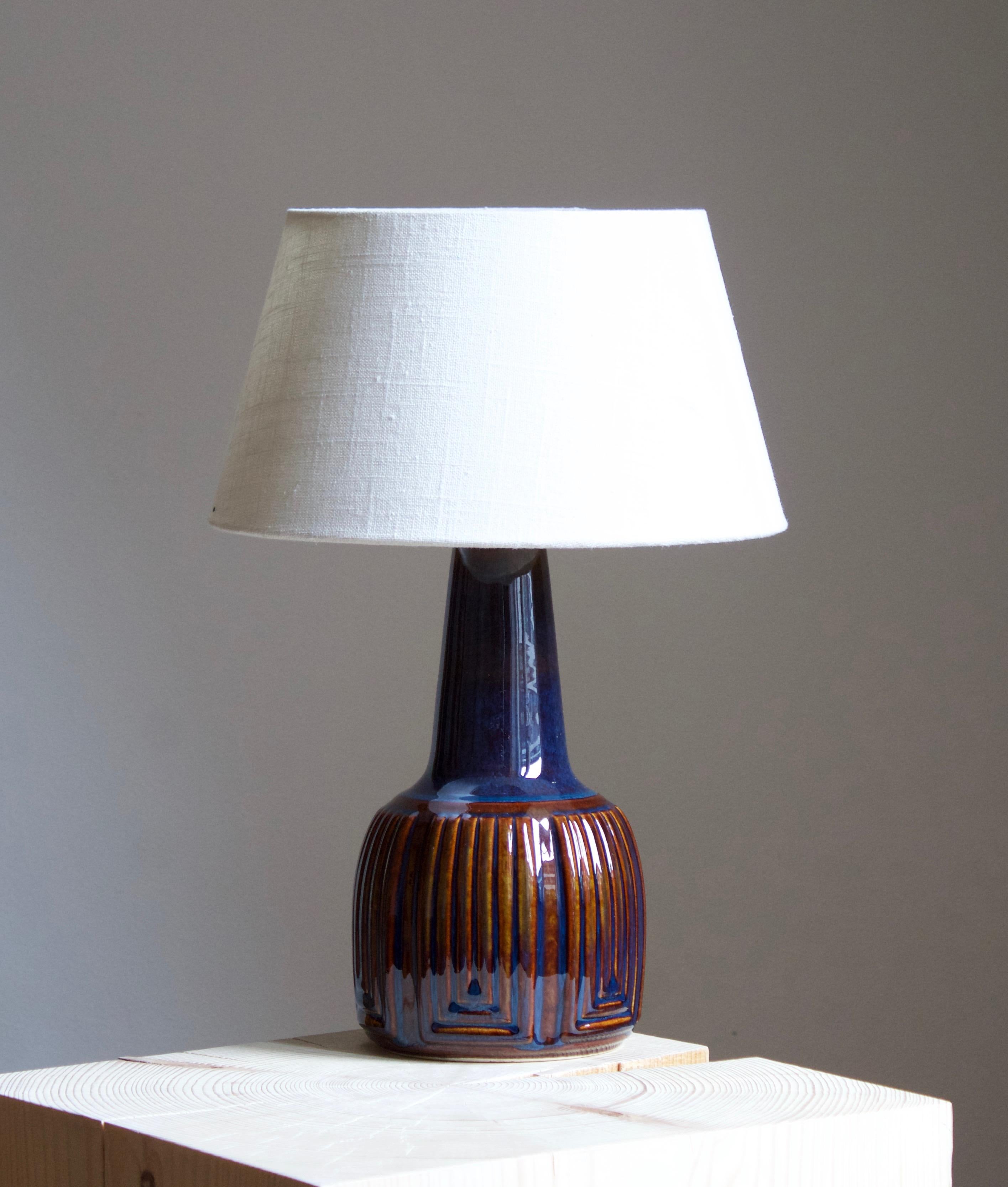 A table lamp produced by Søholm Keramik, located on the island of Bornholm in Denmark. Features a highly artistic glazed and incised decor. 

Sold without lampshade. Stated dimensions exclude the lampshade. Height includes socket.

Glaze features