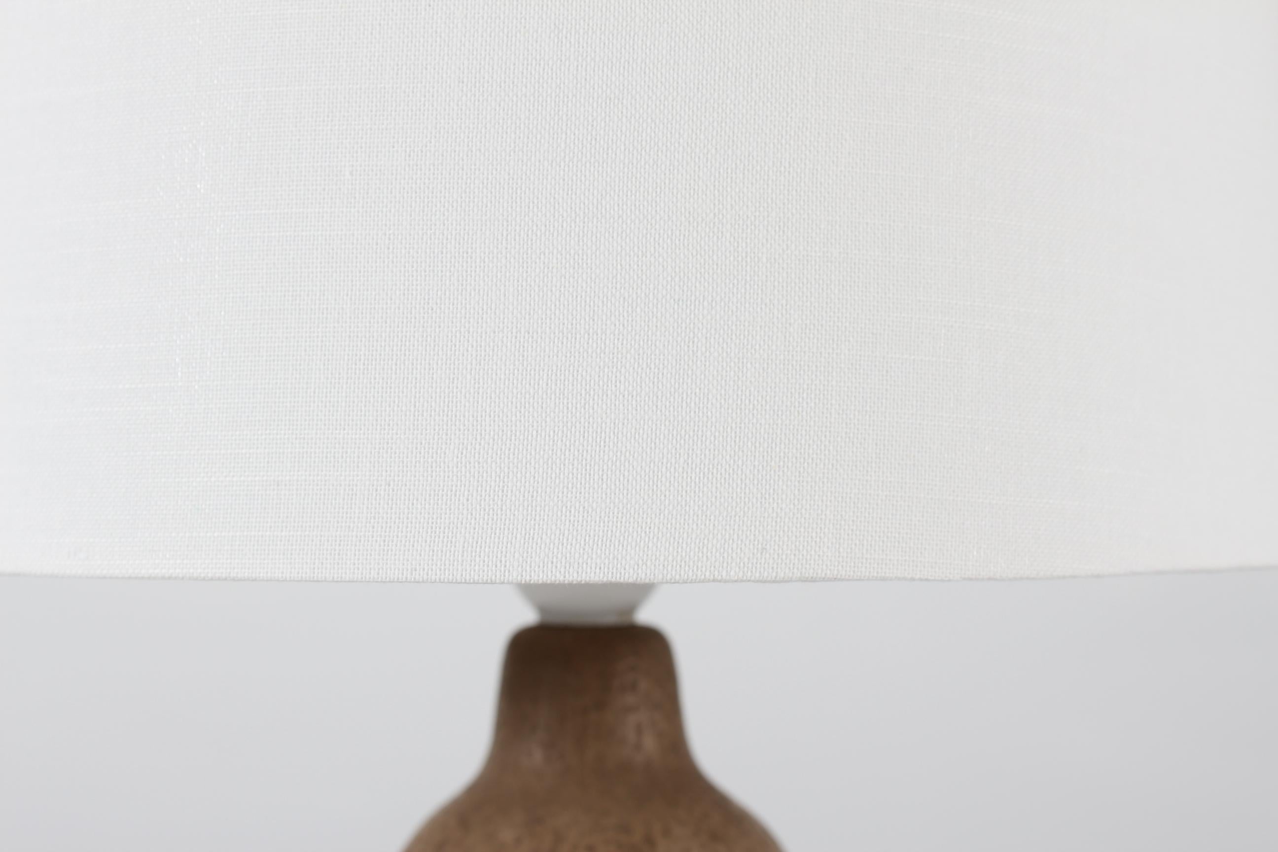 Lampe de table en céramique d'Einar Johansen, fabriquée dans son propre studio de céramique au Danemark, vers les années 1960
Le pied de lampe brun clair non émaillé présente un motif en relief de petites feuilles.

Un nouvel abat-jour conçu et
