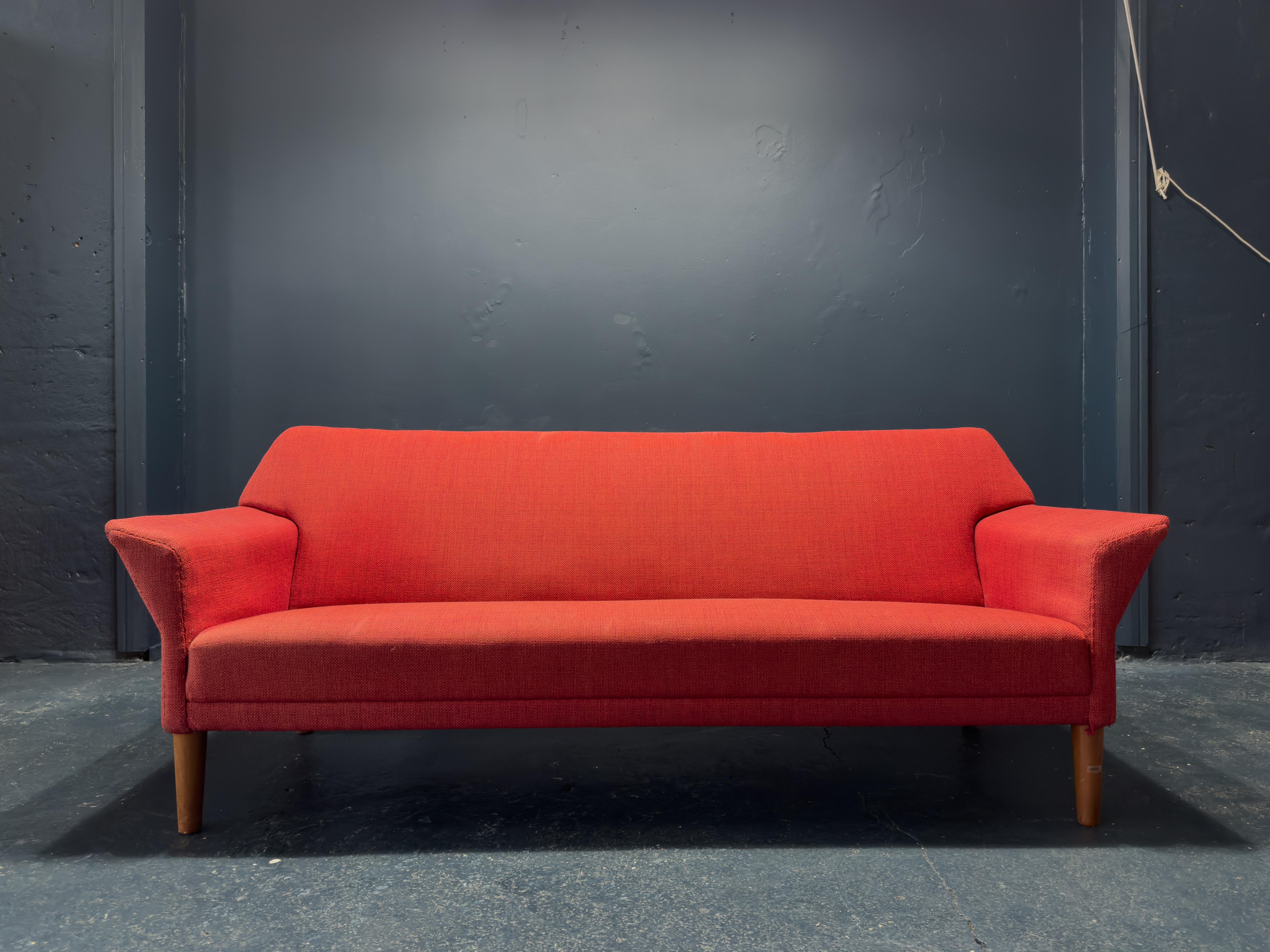 Designed by Ejnar Larsen & Aksel Bender Madsen this three seater sofa is an incredible piece of mid-century design. Upholstered in a striking red woollen fabric the bold colour choice aptly reflects the statement shape and design. Impeccably crafted
