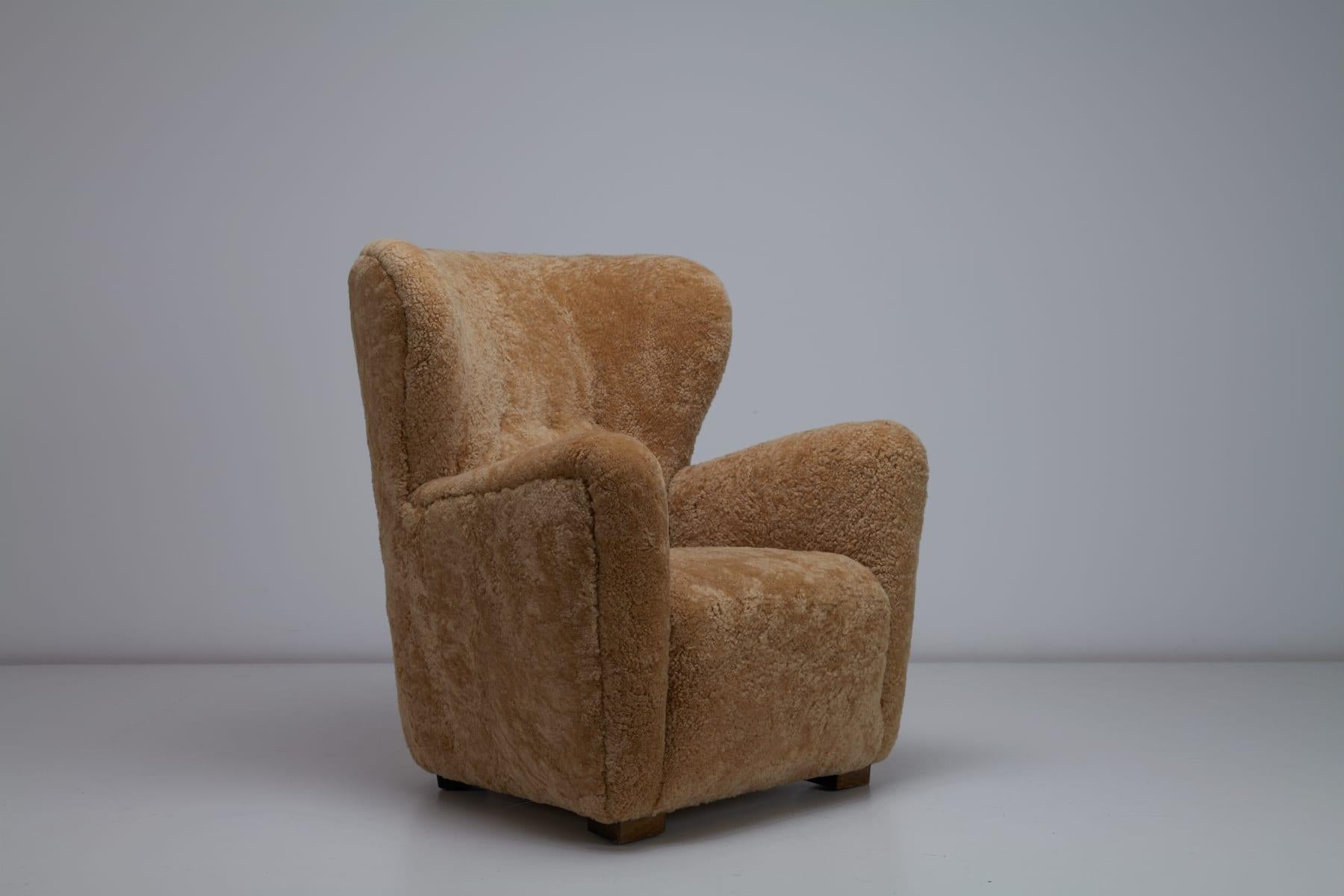Este exquisito sillón danés de respaldo alto de los años 40 desprende elegancia atemporal y encanto de mediados de siglo. Tapizada en lujosa piel de oveja color miel, ofrece confort y calidez, realzando cualquier interior. La silla presenta líneas