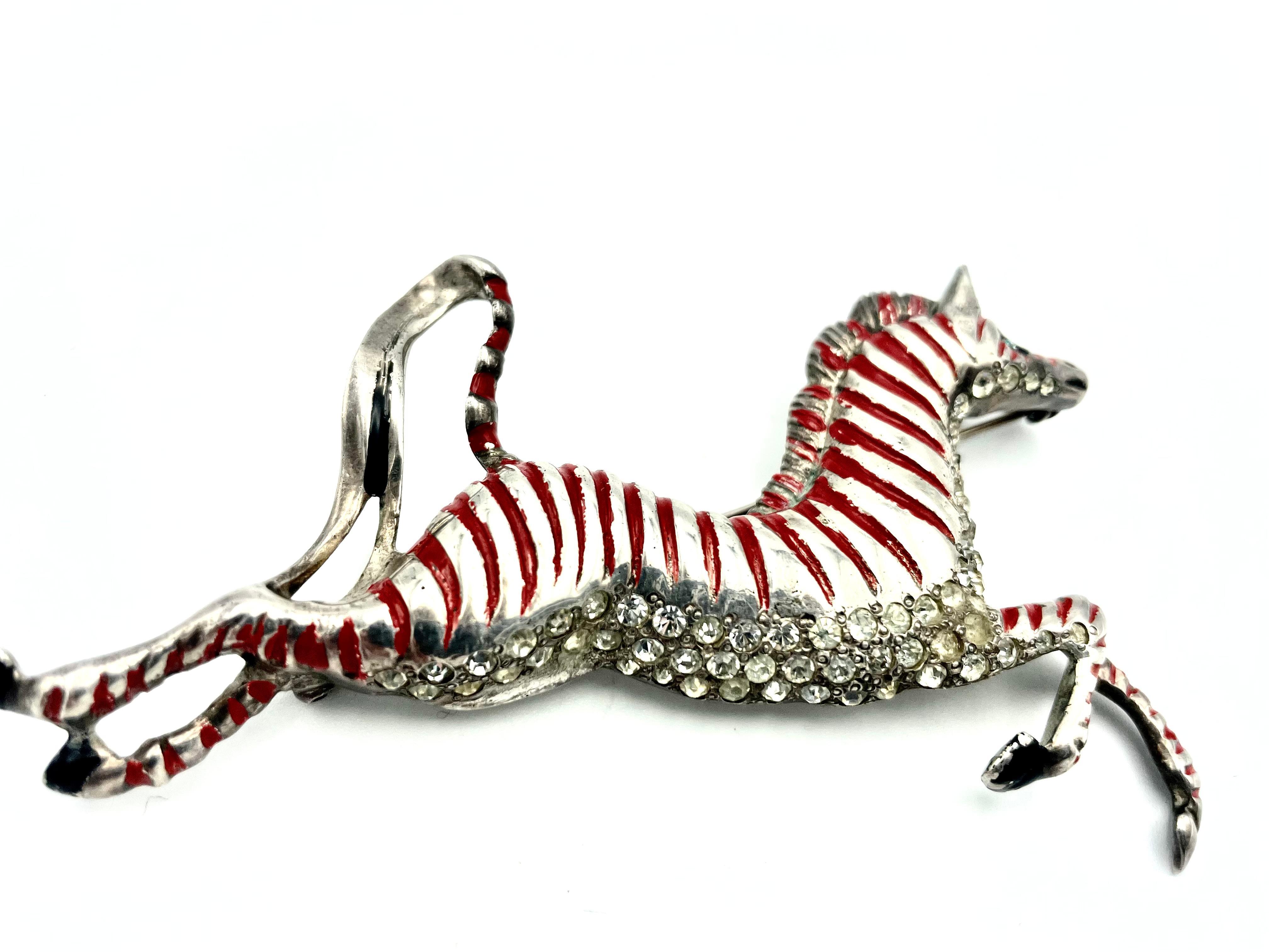 Eisenberg Original galloping Horse pin with flowing mane and tail, Sterling Silver,  red enamelled and rhinestones . 
Sterling was used in 1943 - 44.
Measurement: Size 9 cm x 5 cm, Very good condition, (the shadows on the belly are absent)  book