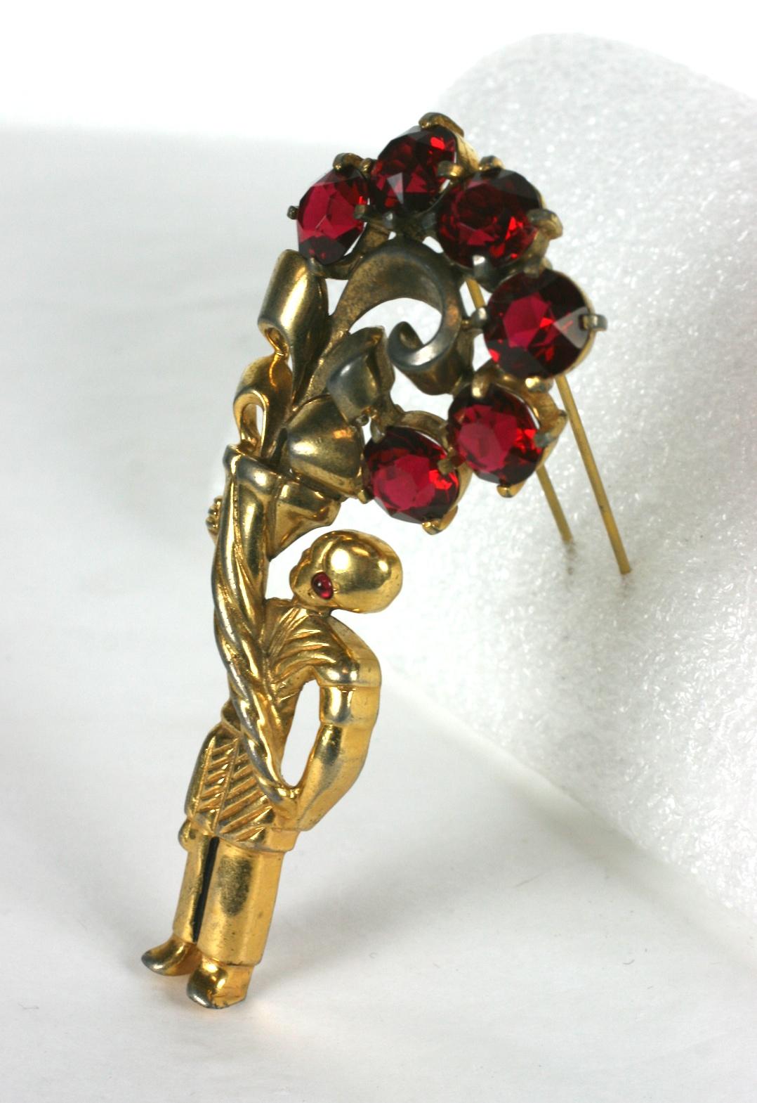 Eisenberg Original gold plate base metal fur clip. The egyptian page figure with focal ruby crystal rhinestone earring, holding an over sized cornucopia with large round faceted ruby crystal branch  flowers and curling leaves. c. 1940.
  Excellent
