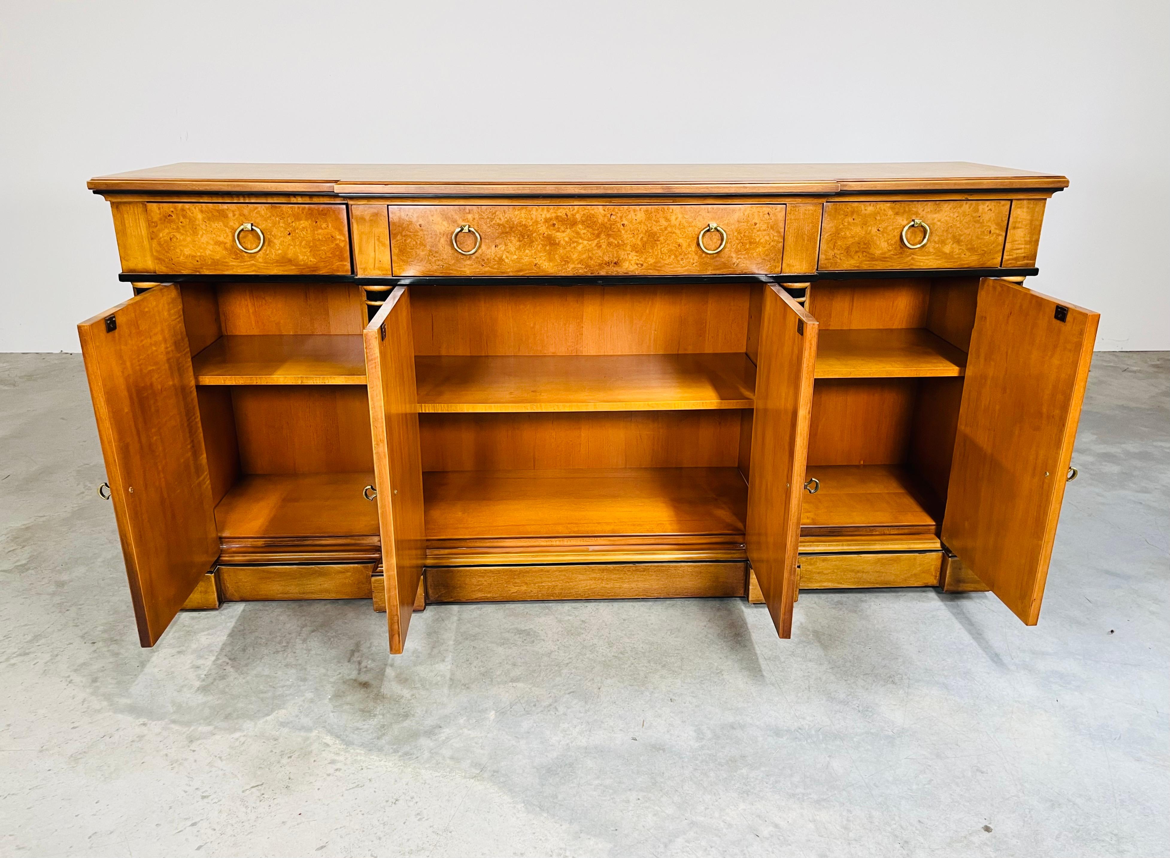 Un buffet audacieux de style Empire. En merisier sculpté, avec des colonnes ébonisées, un plateau en bois de bourgogne et des poignées en laiton en forme de diamant. E.J. Victor Fine Furnishings vers 1990. 
Excellent état général. 
Dimensions :