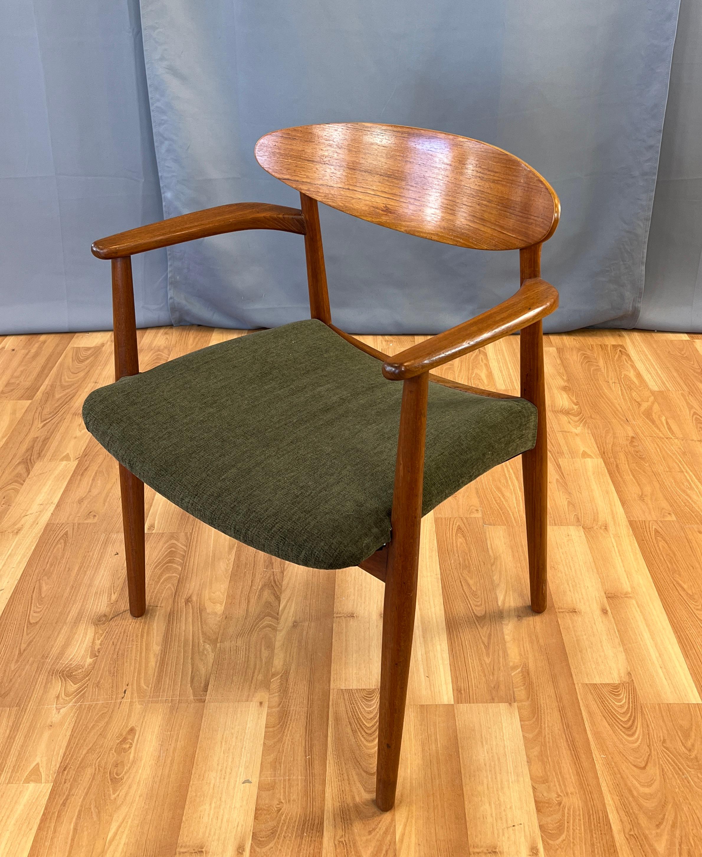 A Ejner Larsen and Aksel Bender Madsen teak armchair with dark green upholstery.
Teak frame, arms curve back, back rest is oval.