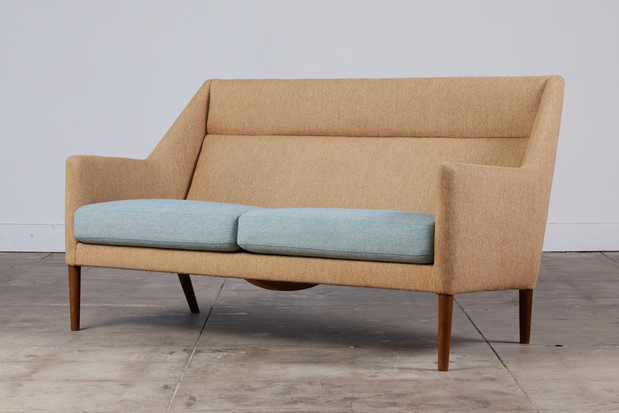 A generous, two-seat sofa designed by Ejner Larsen & Axel Bender Madsen for Fritz Hansen c.1950s, Denmark. The sofa has an elongated wingback chair feeling with its high armrests. The 