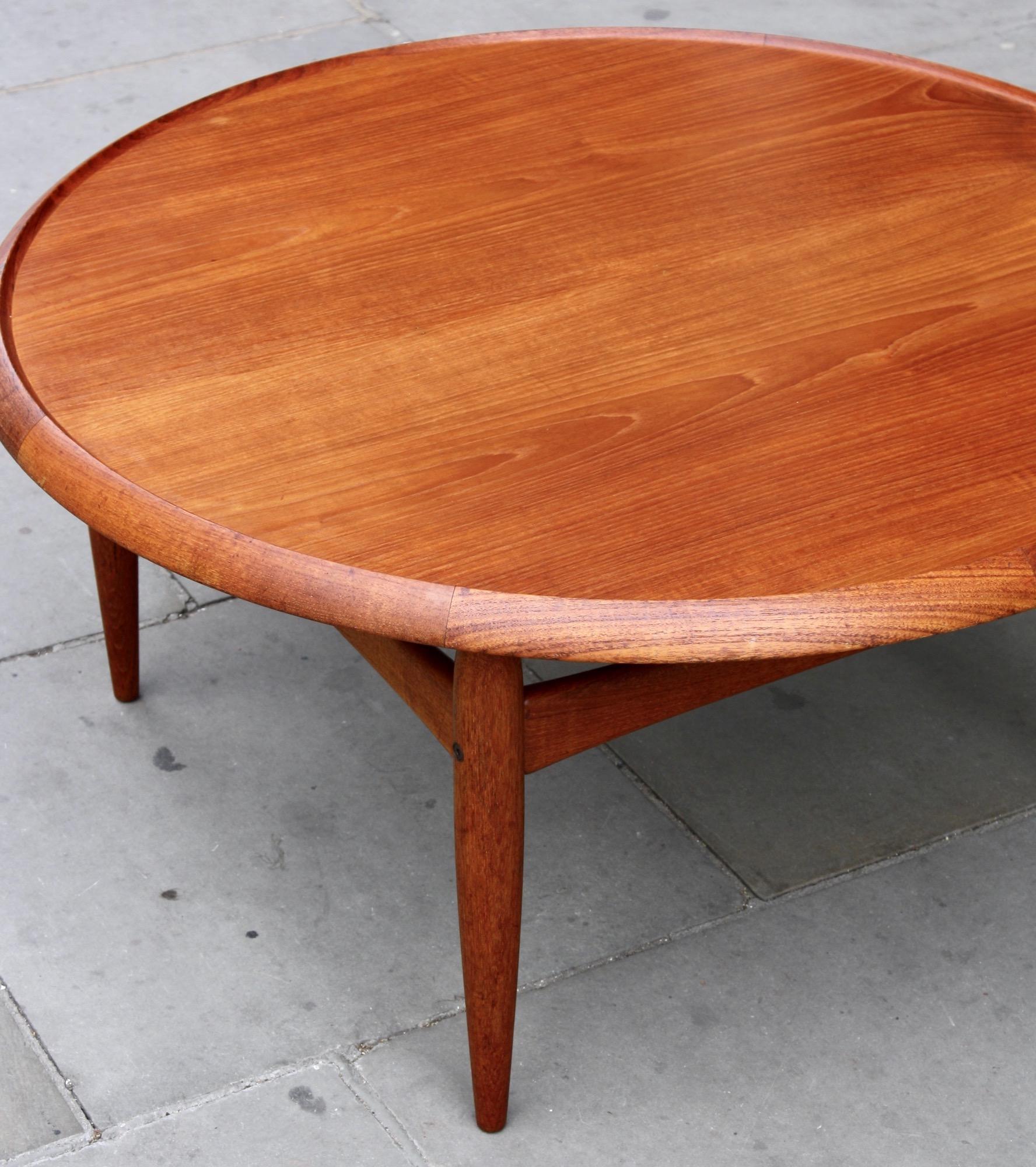 A vintage 1950s teak and formica lounge table. The circular tabletop is reversible, inlaid with black formica on one side and teak on the other. The tapered frame is carved of solid teak. Designed by Ejvind. A. Johansson in 1955, and manufactured by