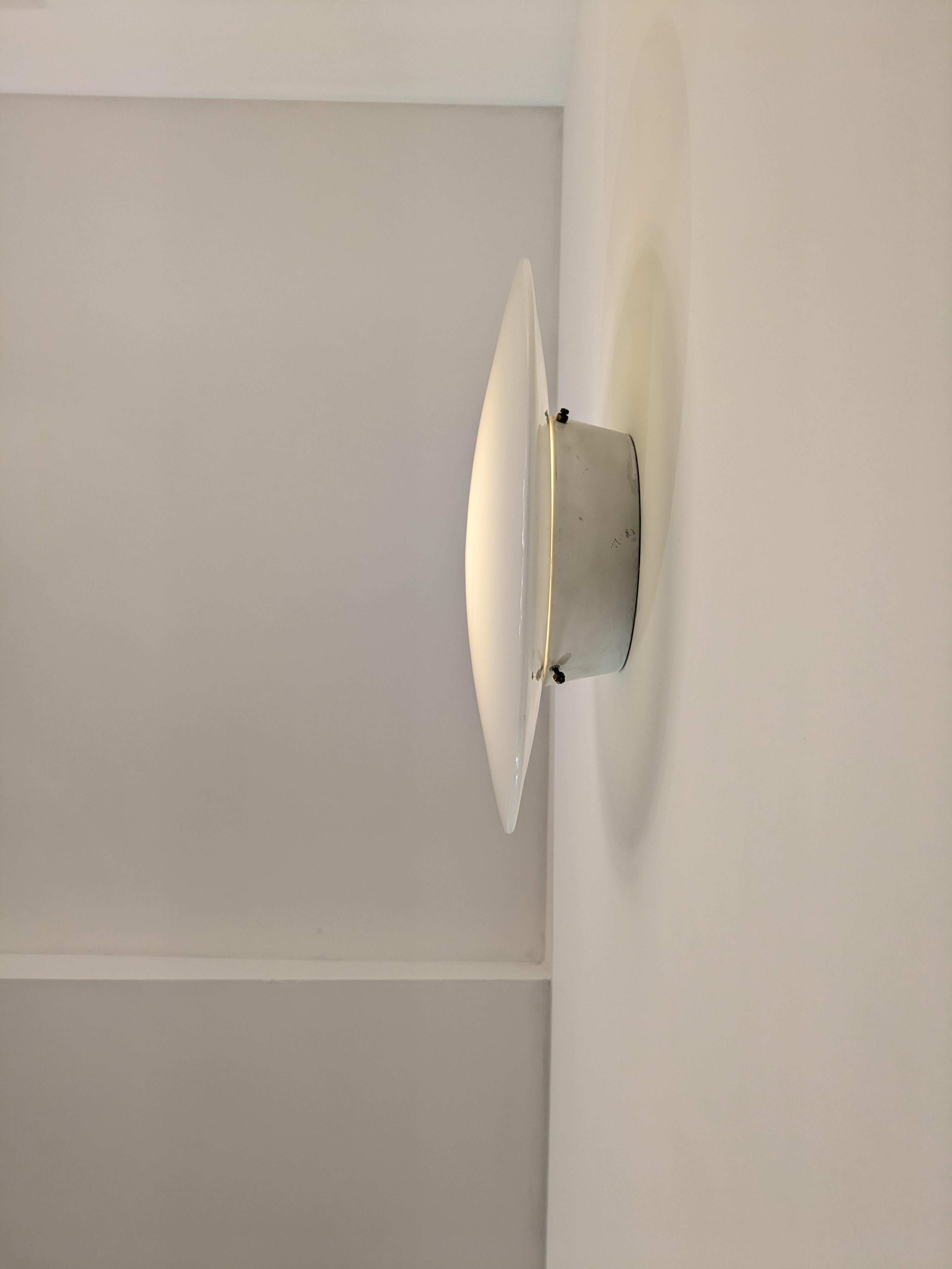 Diese Wandleuchte, die auch als Deckenleuchte verwendet werden kann, wurde ursprünglich 1959 für das Rathaus von Rodovre entworfen und von der berühmten dänischen Marke Louis Poulsen herausgegeben. 
Der Designer ist Arne Jacobsen, der auch für