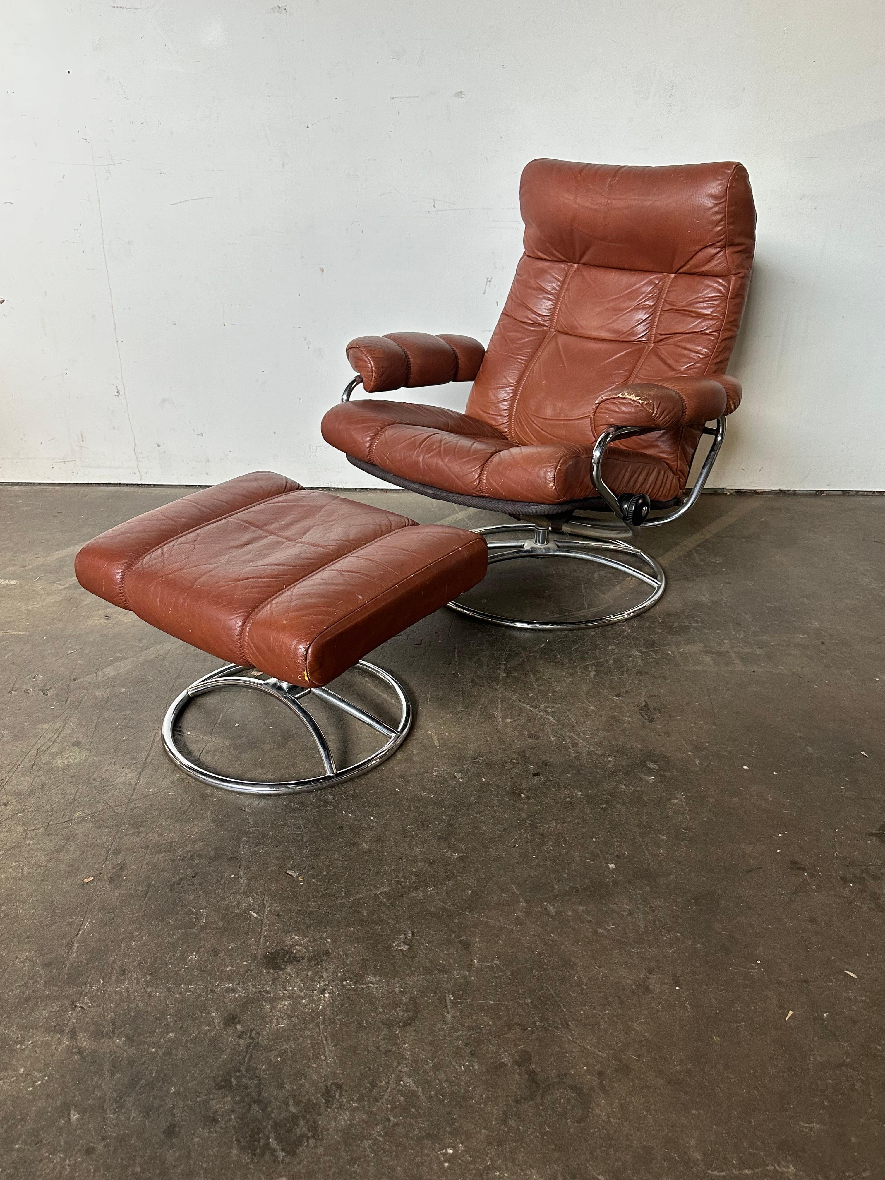 Classic Ekornes Stressless lounge chair and ottoman. Leather cushions in burnet orange on chrome metal swivel bases. No tears in leather. Normal signs of use. Minor creasing/losses to leather. Multiple adjustable angles to sit up, lounge, and lie