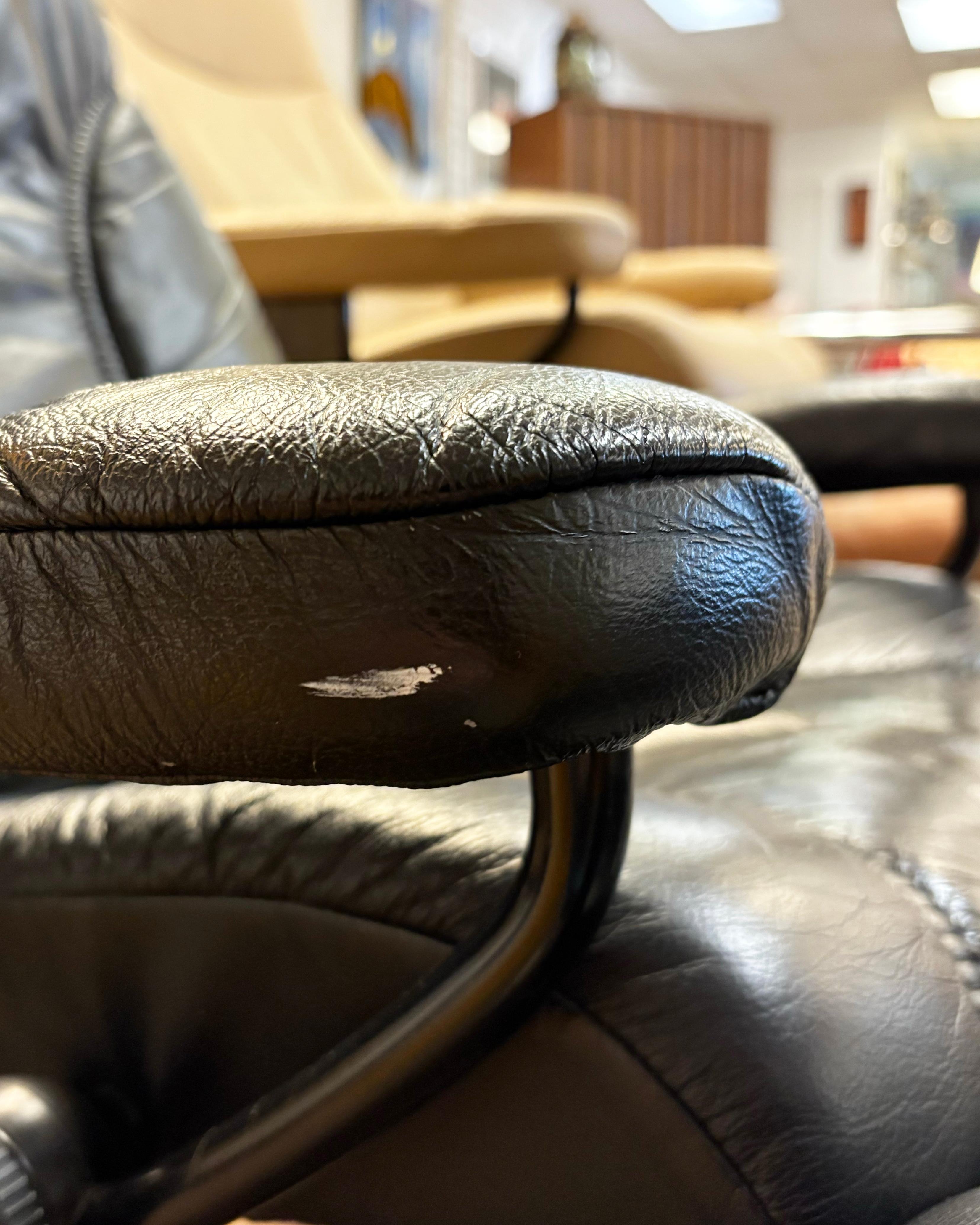 Ekornes Stressless Black Leather Swivel Recliner Chair with an Ottoman. The chair features beautiful black leather and a dark wood swivel base. It comes with an adjustable ottoman. The chair is incredibly comfortable and in great condition, with