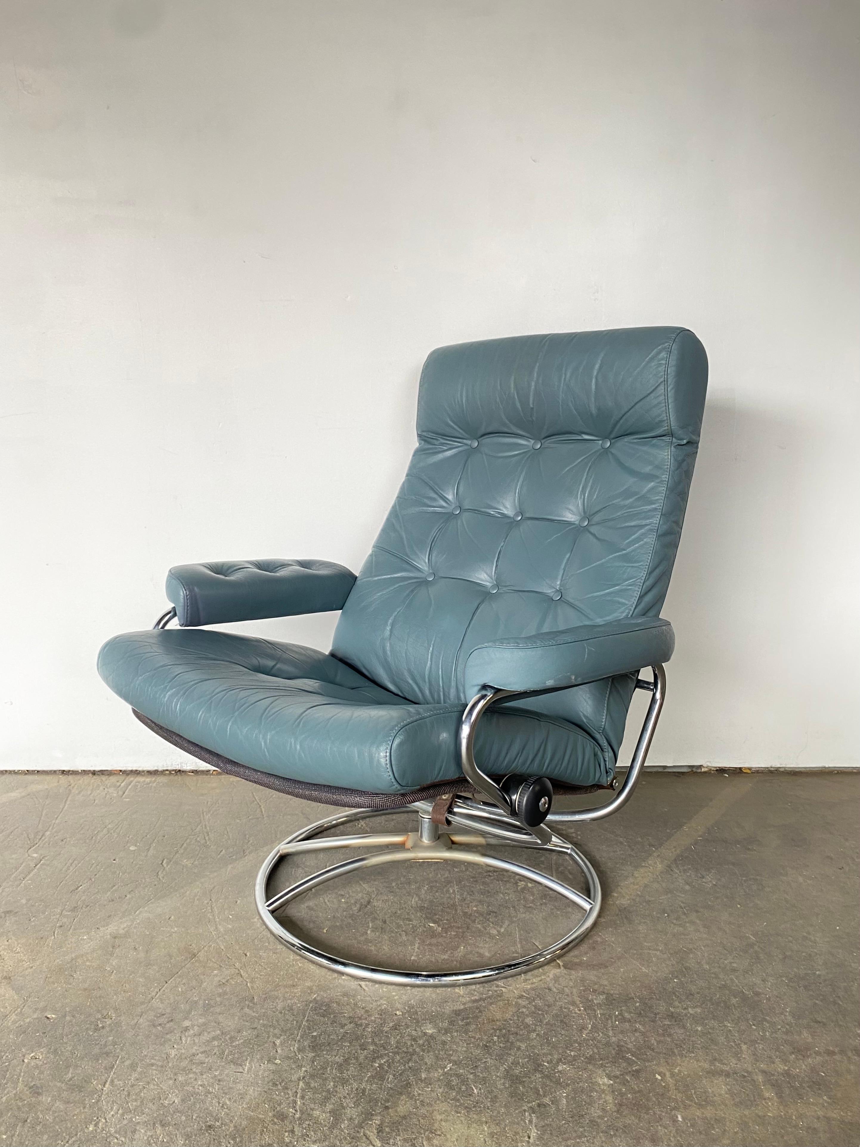 Ekornes Stressless reclining lounge chair and ottoman from the 1970s. Elegant mid century Scandinavian design with tubular bent chrome frame and original blue tufted leather cushion. Lounge comfortably at any angle in this timeless design.