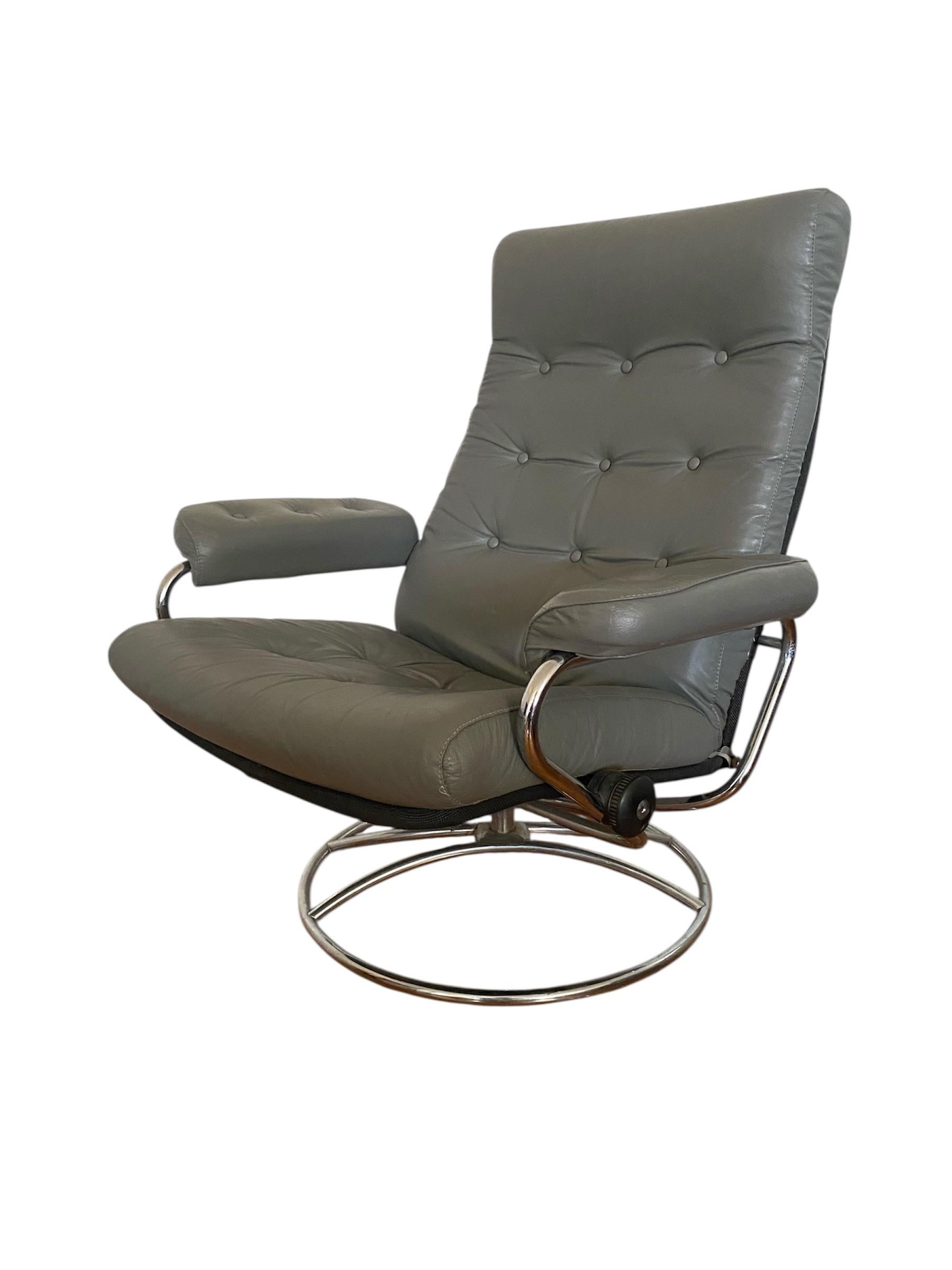 Sillón reclinable Ekornes Stressless. Elegante diseño escandinavo de mediados de siglo con estructura tubular de cromo curvado y cojín de piel gris con botones. Relájate cómodamente en cualquier ángulo con este diseño atemporal.