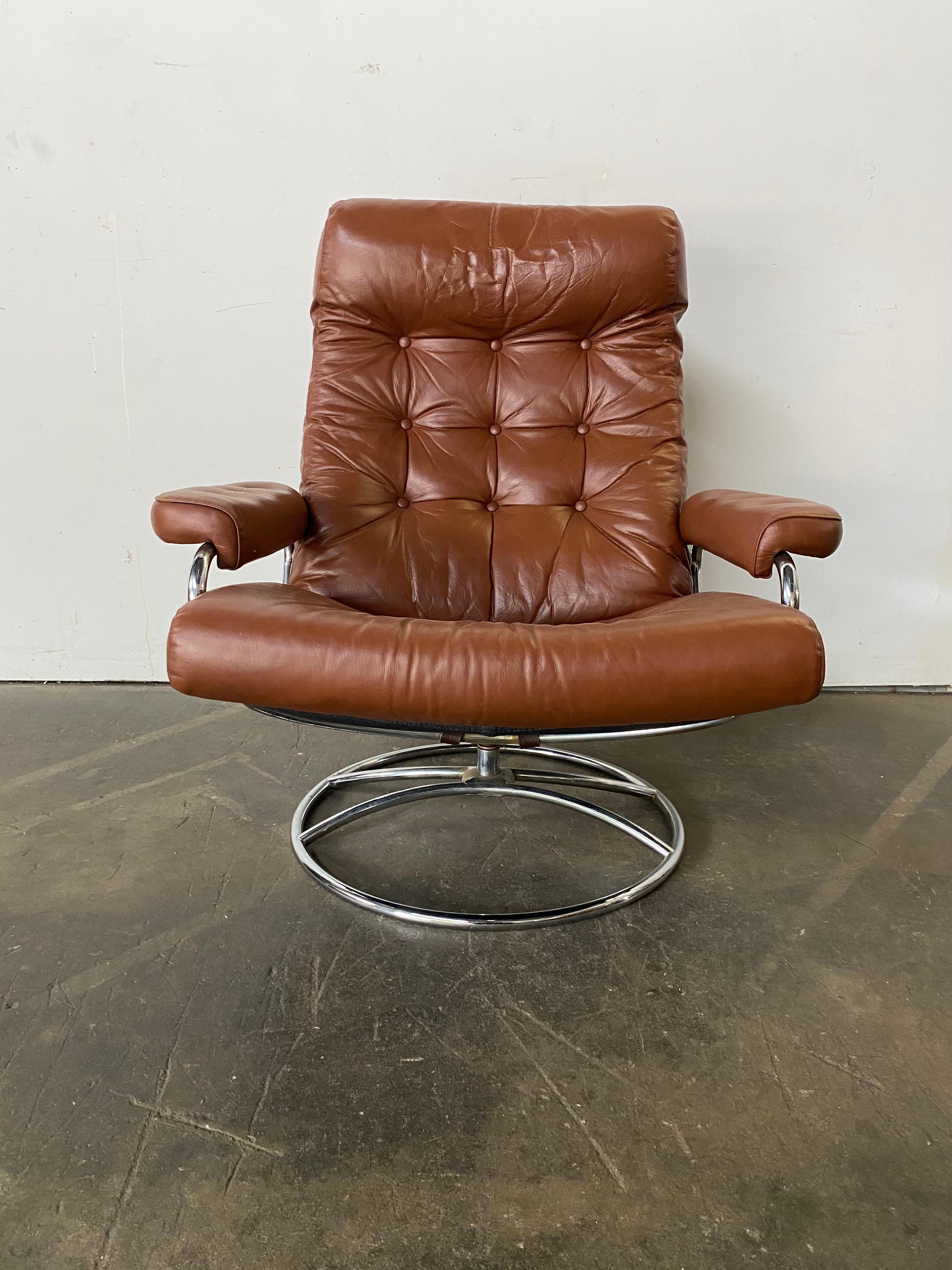 Ekornes Stressless reclining lounge chair. Elegant mid century Scandinavian design with tubular bent chrome frame and burnt orange leather cushion with buttons. Lounge at any angle in comfort with this timeless design.
