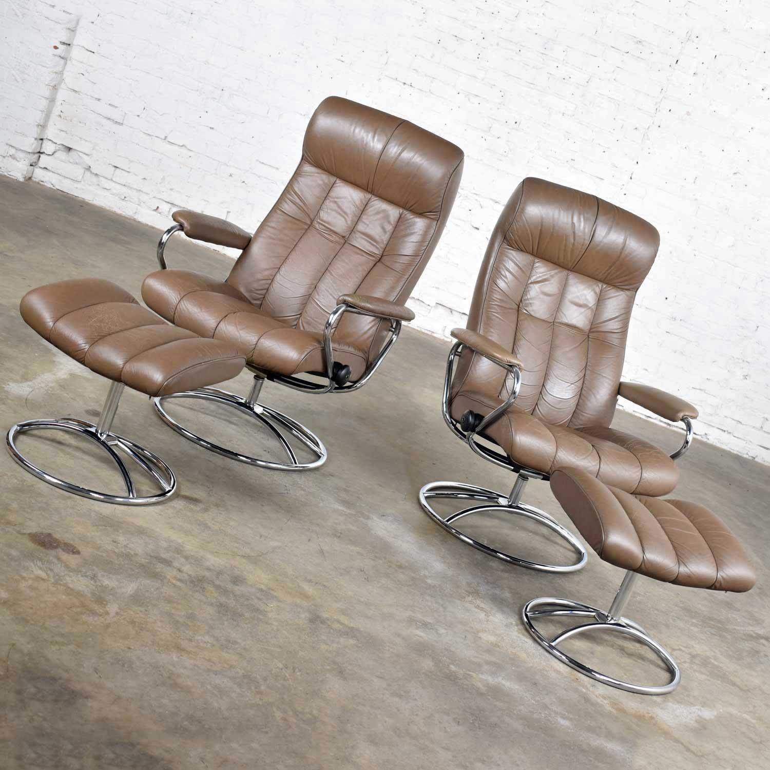 Wonderful pair of vintage Ekornes Stressless Scandinavian lounge chairs and ottomans. Comprised of taupe leather and chrome bases. Very good vintage condition. The arm rests on one chair have been reupholstered but may have a slight color