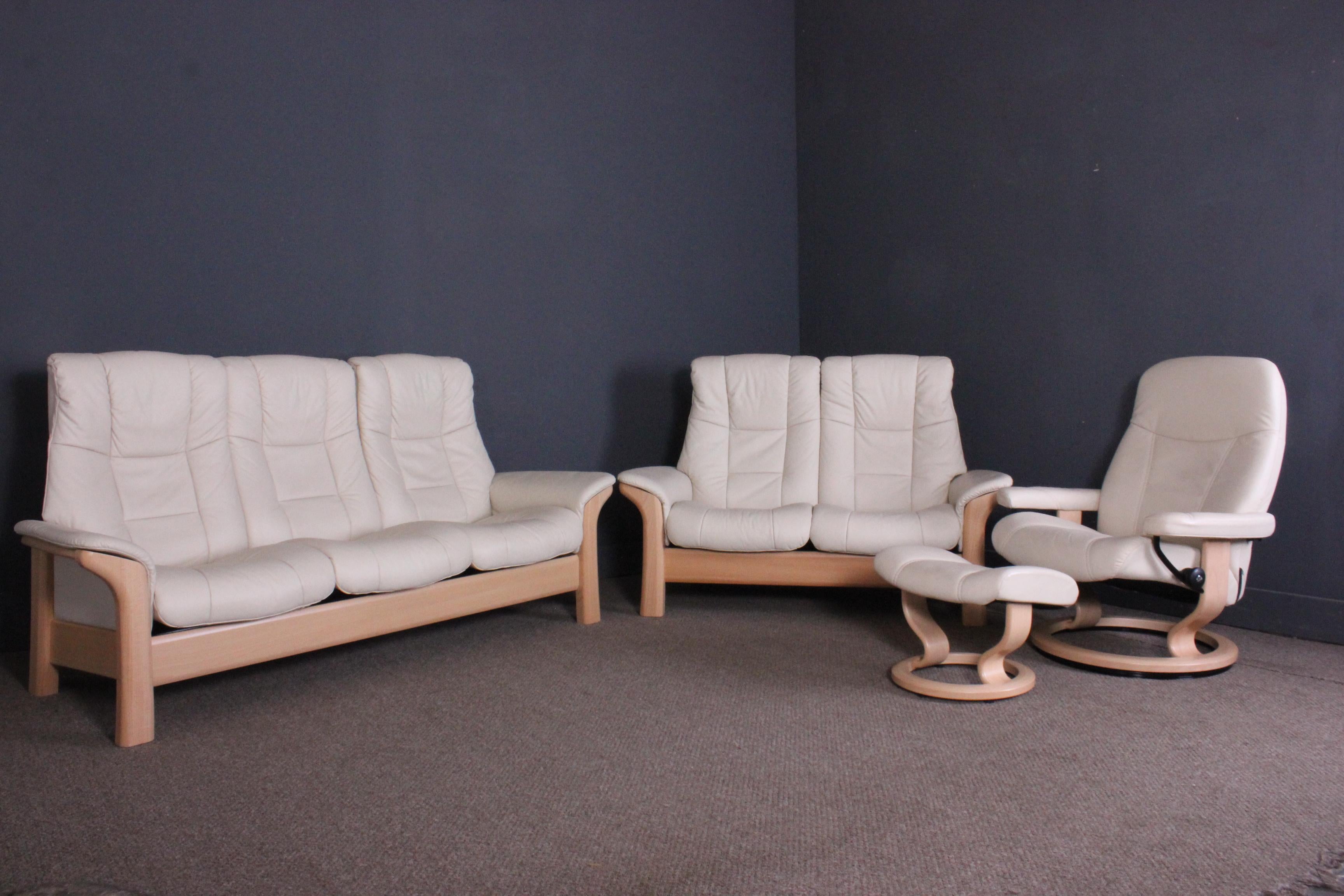 Beautiful Ekornes stressless windsor leather sofas with a matching stressless ambassador leather chair and footstool. They are all ivory in color and are in excellent condition with no marks or damage to either the leather or the wooden bases. Both