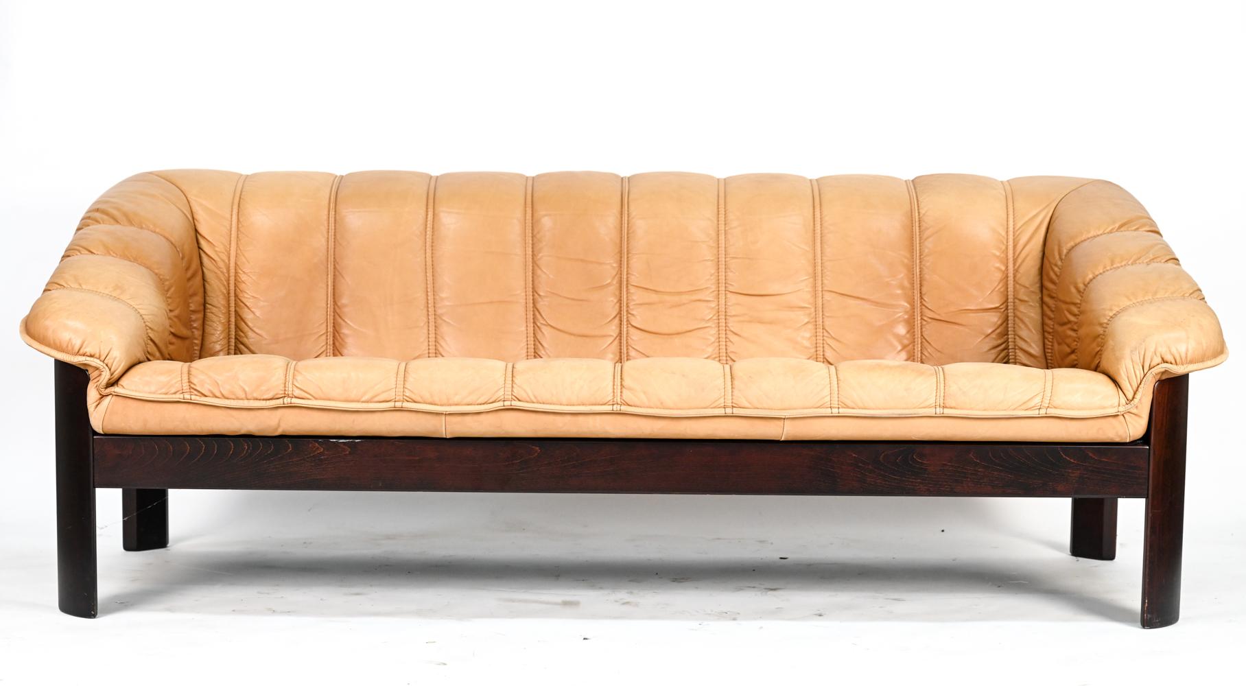 A superb Norwegian sofa suite comprising of a sofa and loveseat by Ekorness, upholstered in handsomely patinated, stitched brandy leather.
