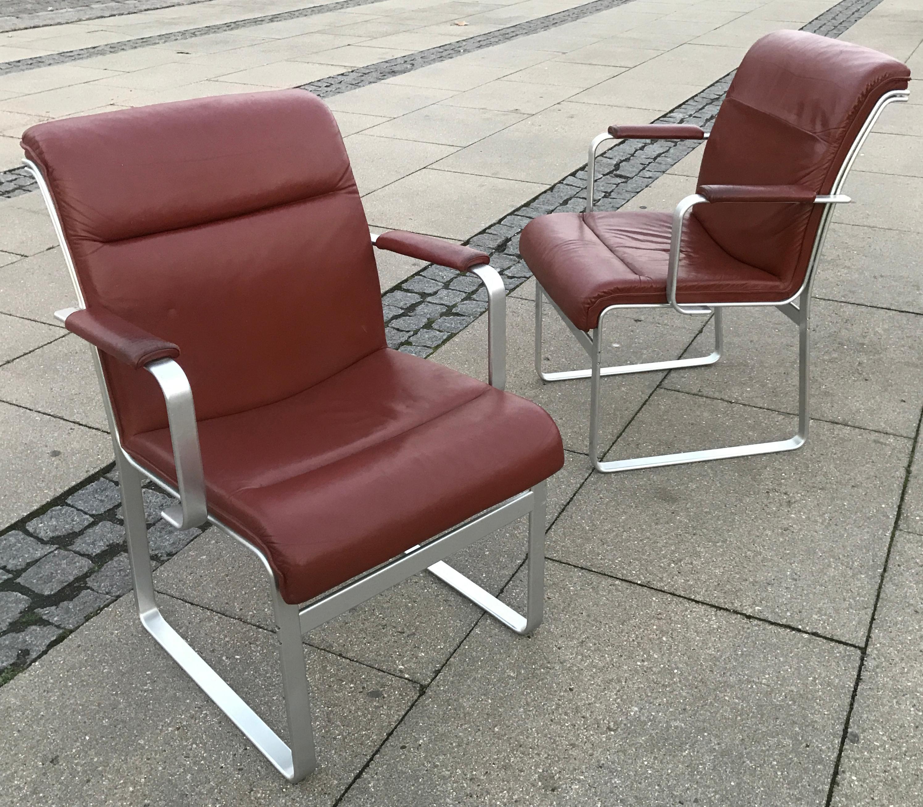 JOC manufactured pair of armchairs designed by Karl Erik Ekselius (Swedish 1914-1998) in the 1960s. Cognac leather upholstery with natural patina. Frame in matte brushed or polished aluminum profiles. A beautiful set of design icons from the madmen