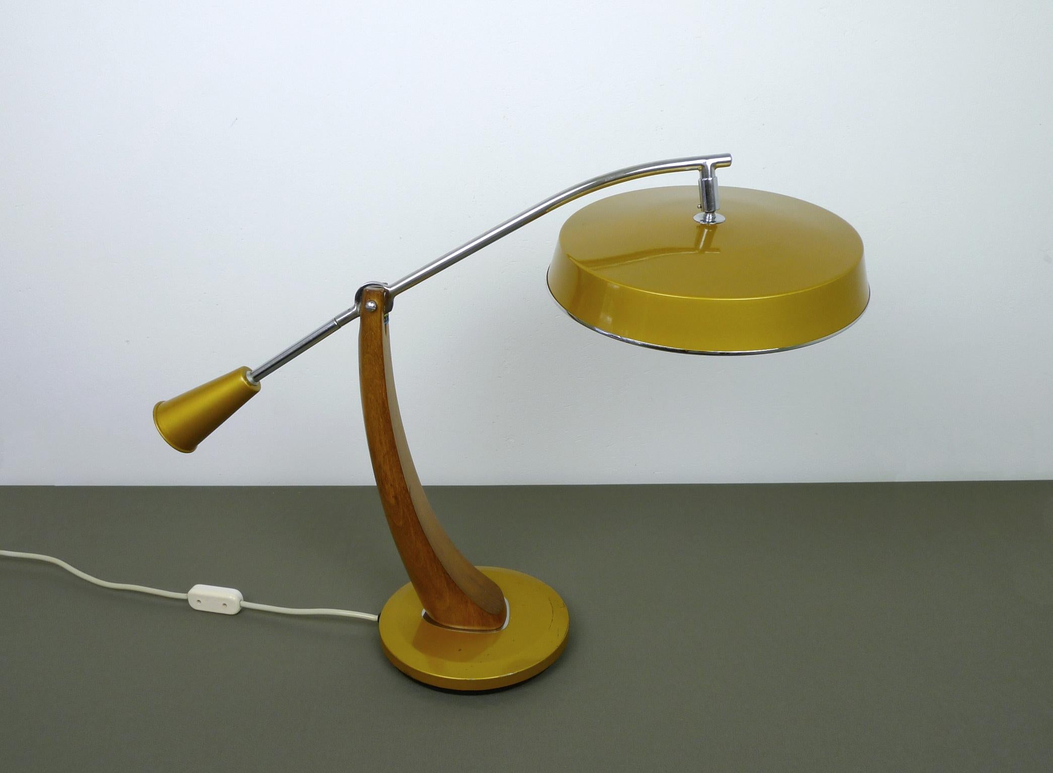 This large model El Presidente Péndulo desk lamp was produced by the Spanish manufacturer Lamparas FASE in the 1960s. 
It is made of metal and supported by a curved stand made of solid teak. The joints and the cantilever arm are plated in chrome