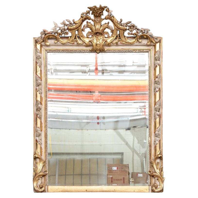 A fine Gilt Mirror with intricately carved crest with Floral motif, the frame with swirled contrasting bands of gold with contrasting white floral elements on a diamond pattern background. Restoration recommended. 

The Mirror measures 43” high by