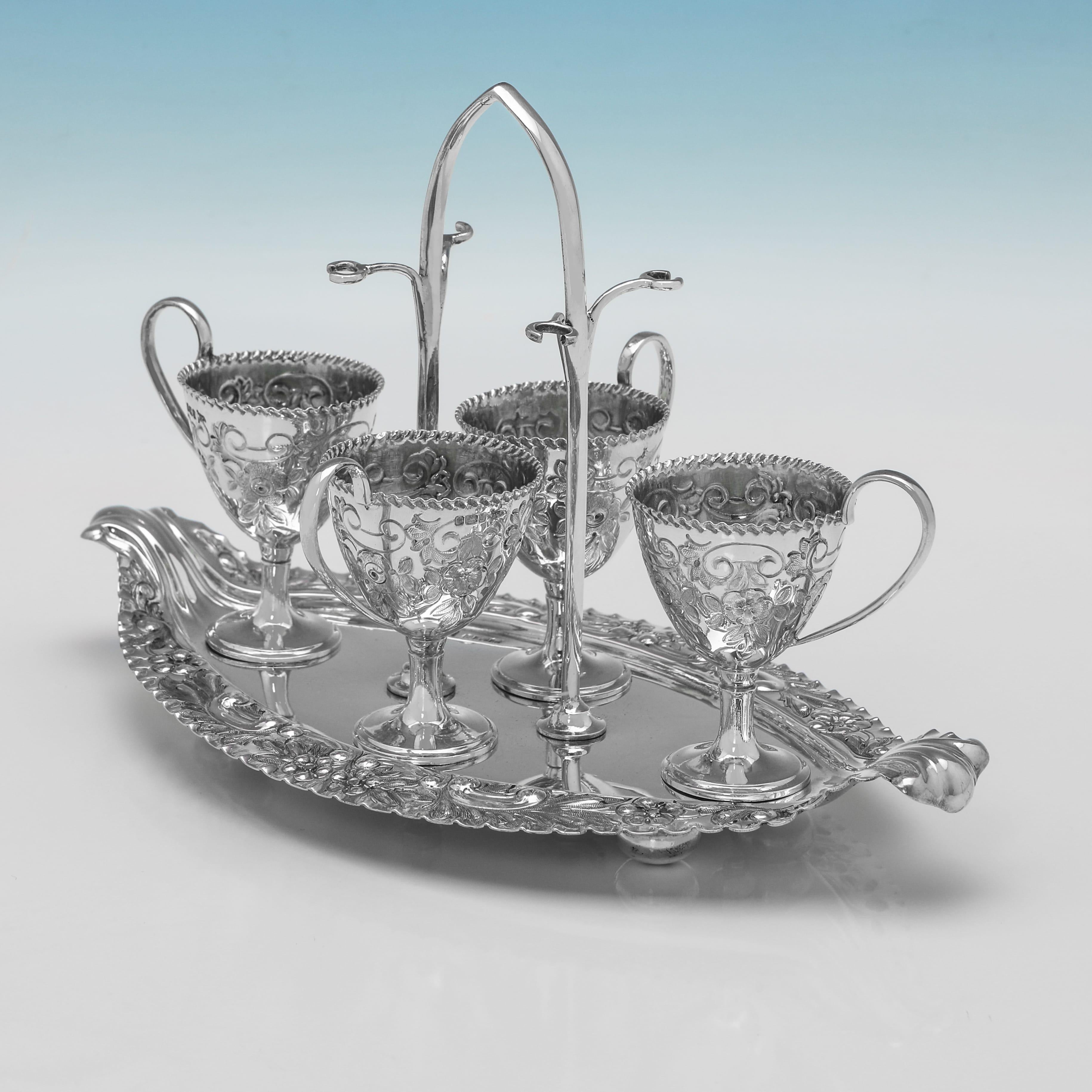 Hallmarked in Sheffield in 1903 by Walker 
Hall this elaborate Edwardian antique sterling silver egg cruet comprises an oval tray and four egg cups. The tray has a repoussé rim with floral and foliate decoration and a central arched handle. The