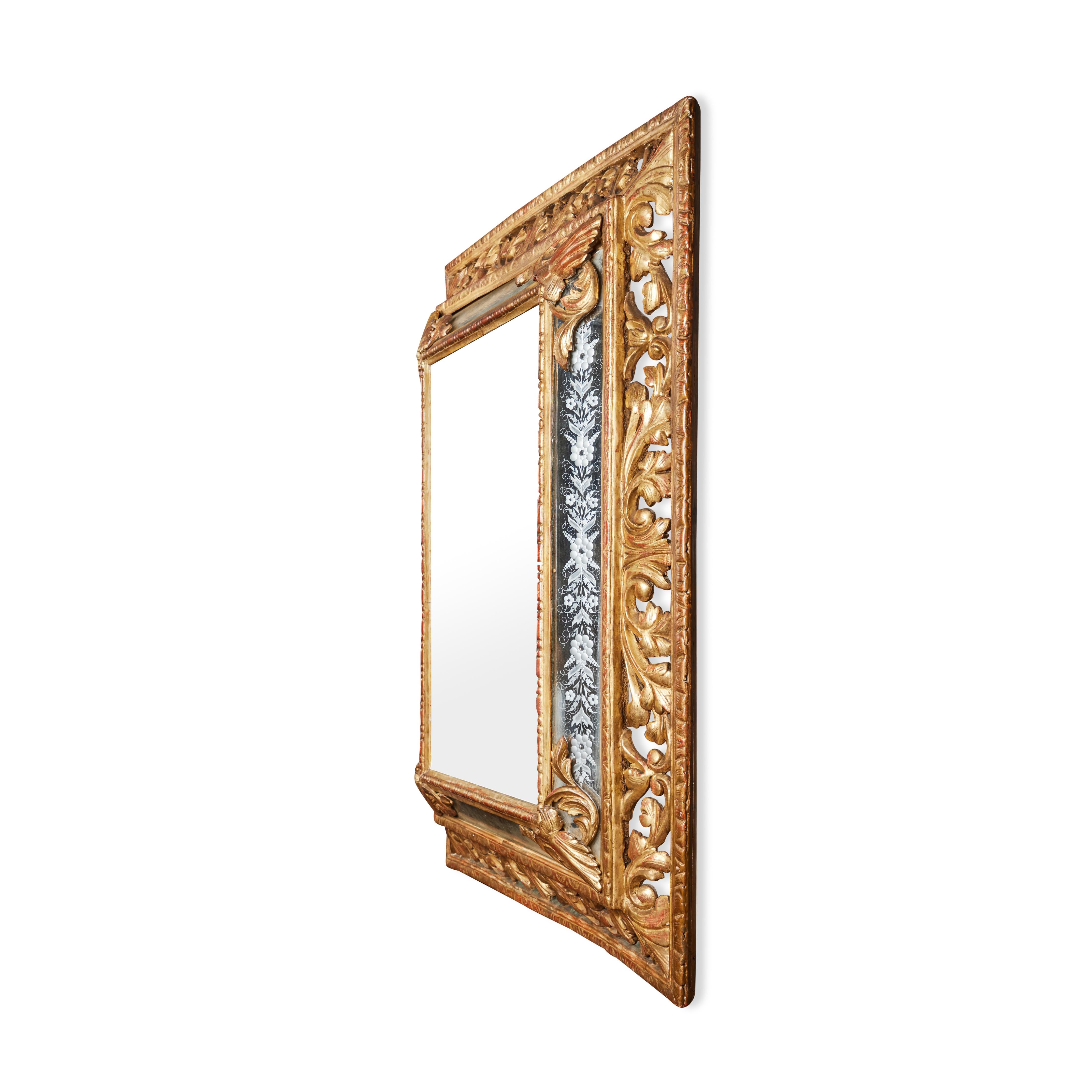Elaborately hand carved and gilded, stepped mirror with etched glass insets featuring floral designs. 