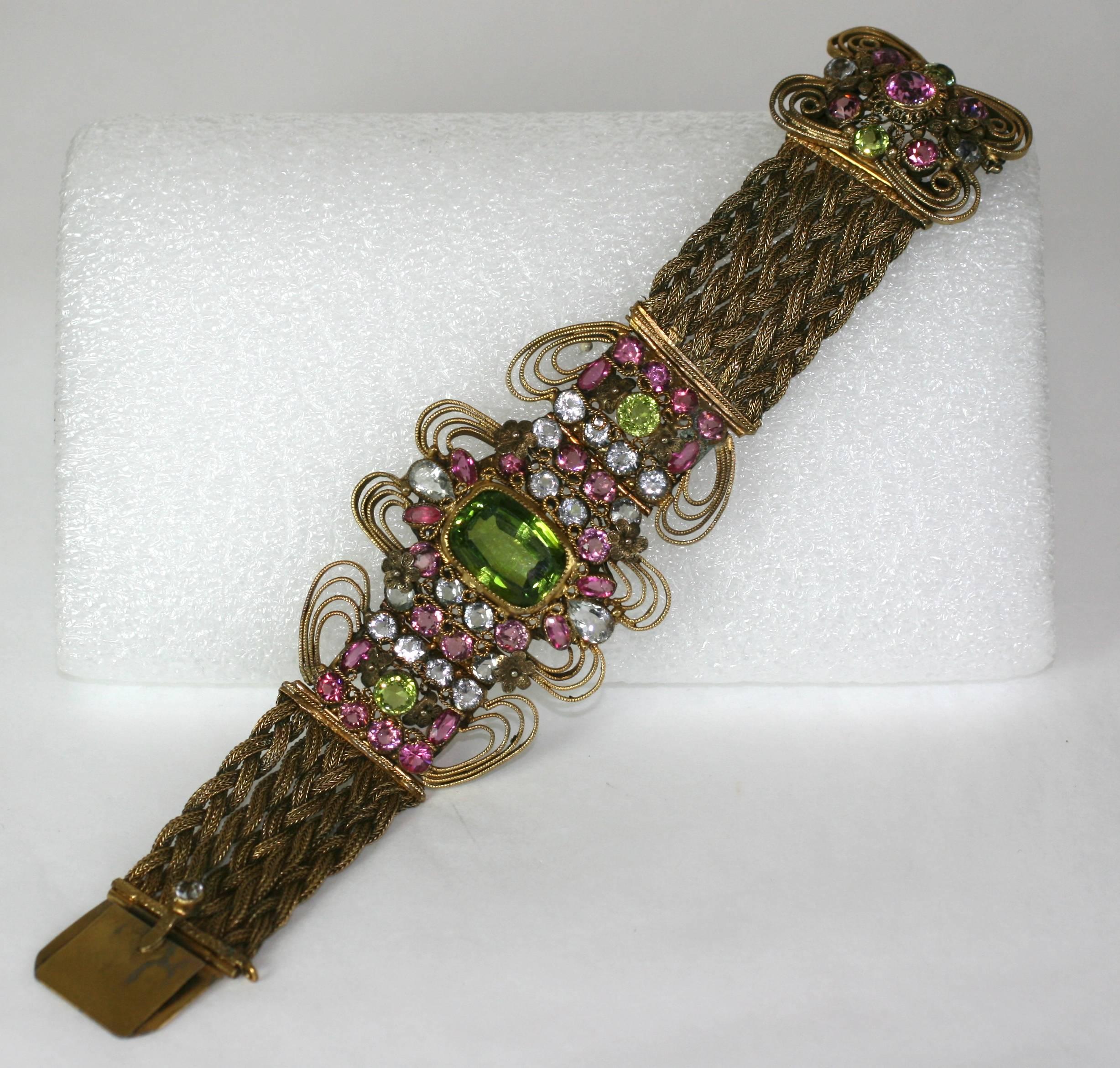 Stunning Jeweled Bracelet attributed to the Hobe Company. Beautifully hand crafted with colored pastes in the elaborate, Baroque style for which Hobe is known. A large faux peridot is centered around crystal, pink and green pastes in elaborate wire