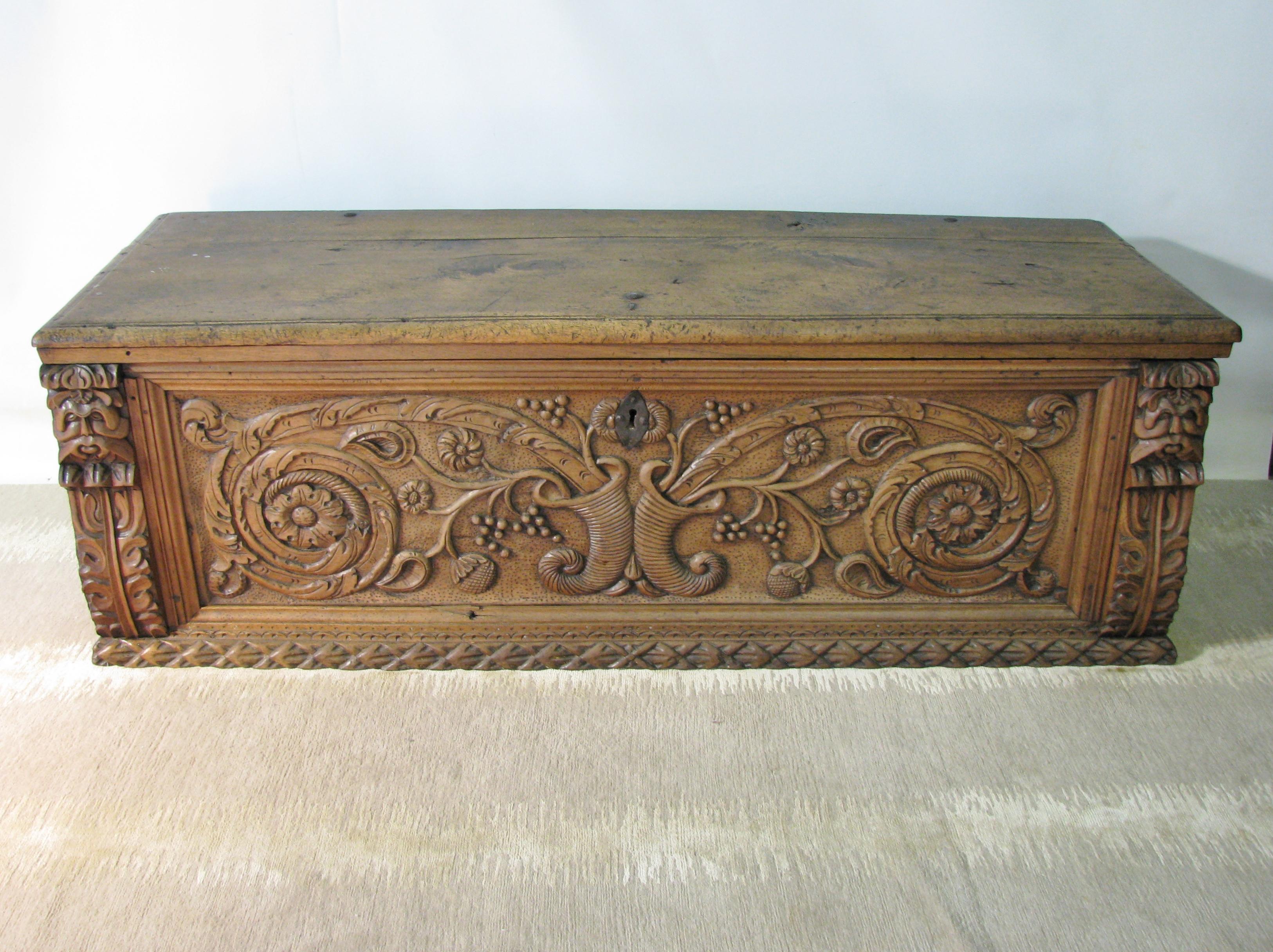 Beautifully crafted early 18th century Italian walnut cassone, or trunk. Heavy piece, made of thick, solid planks of wood. The front is deeply carved with an elaborate scroll-work motif emanating from twin cornucopias. The scrolls incorporate grapes