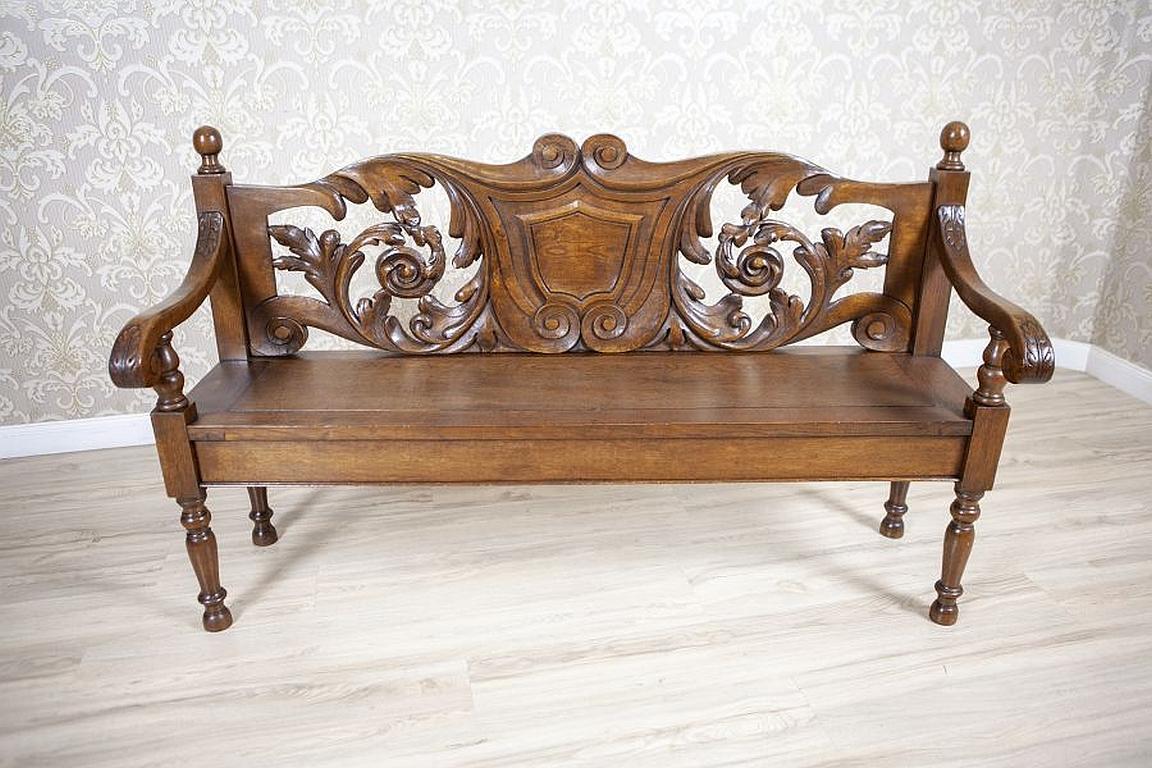 Elaborately carved oak bench from the early 20th century

We present you this oak bench supported on four rounded legs, with armrests of a slightly wavy shape. The whole is decorated with carved patterns in the shape of oak leaves.
The openwork