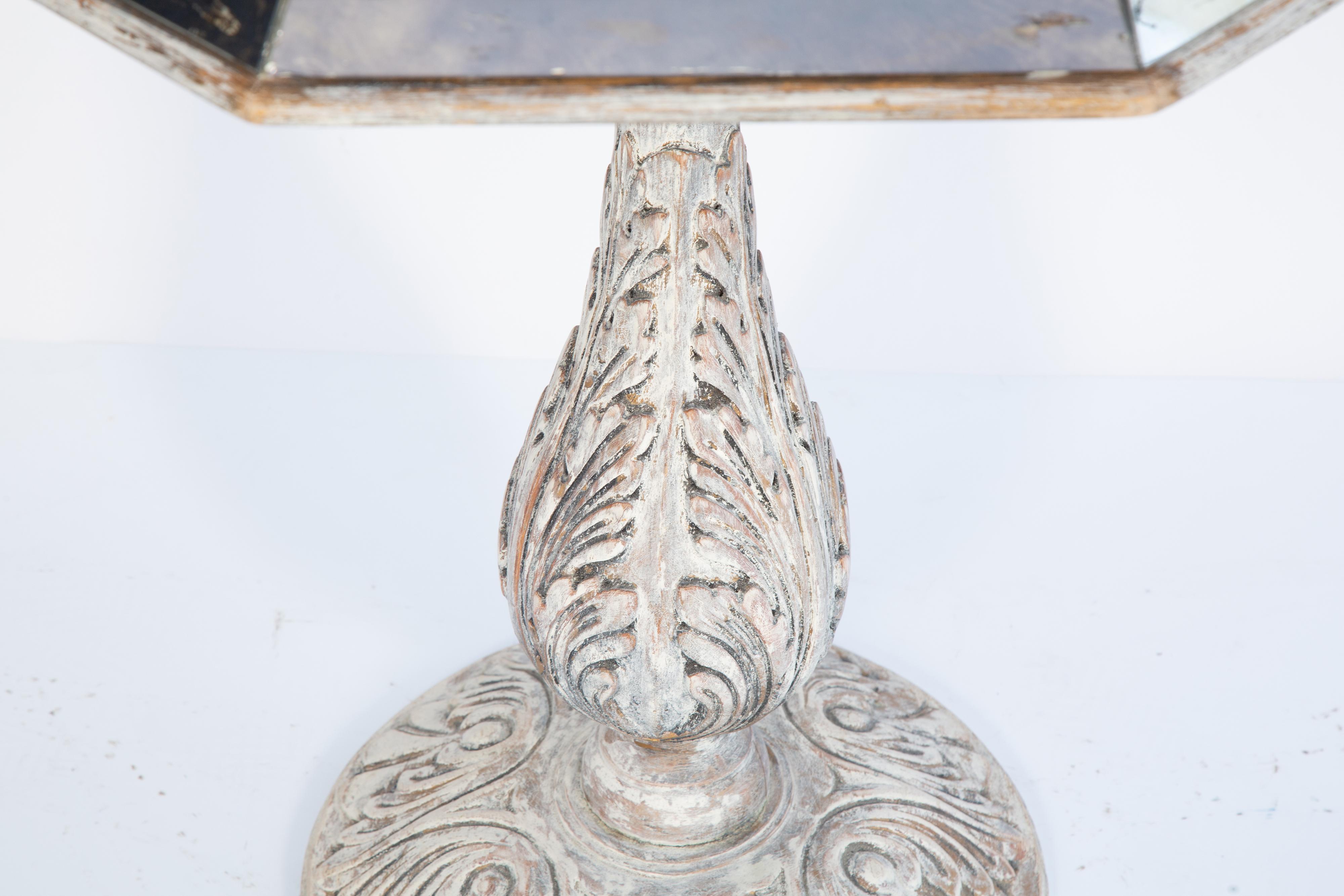 Occasional table, having an octagonal top of antique mirror, with canted apron, raised on vase-form pedestal base, exuberantly hand carved with foliate details, ending in round foot, mottled painted finish with desirable wear.

Please contact us for
