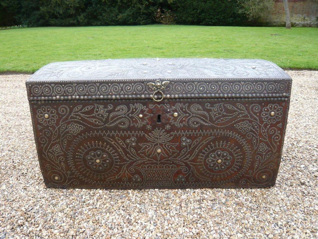 A fantastic 17th century Dutch traveling trunk in russia leather with elaborate brass stud decoration to front and top in the form of swirling flowers in geometric patterns with central winged cherub pull plate. Interior freshly lined.