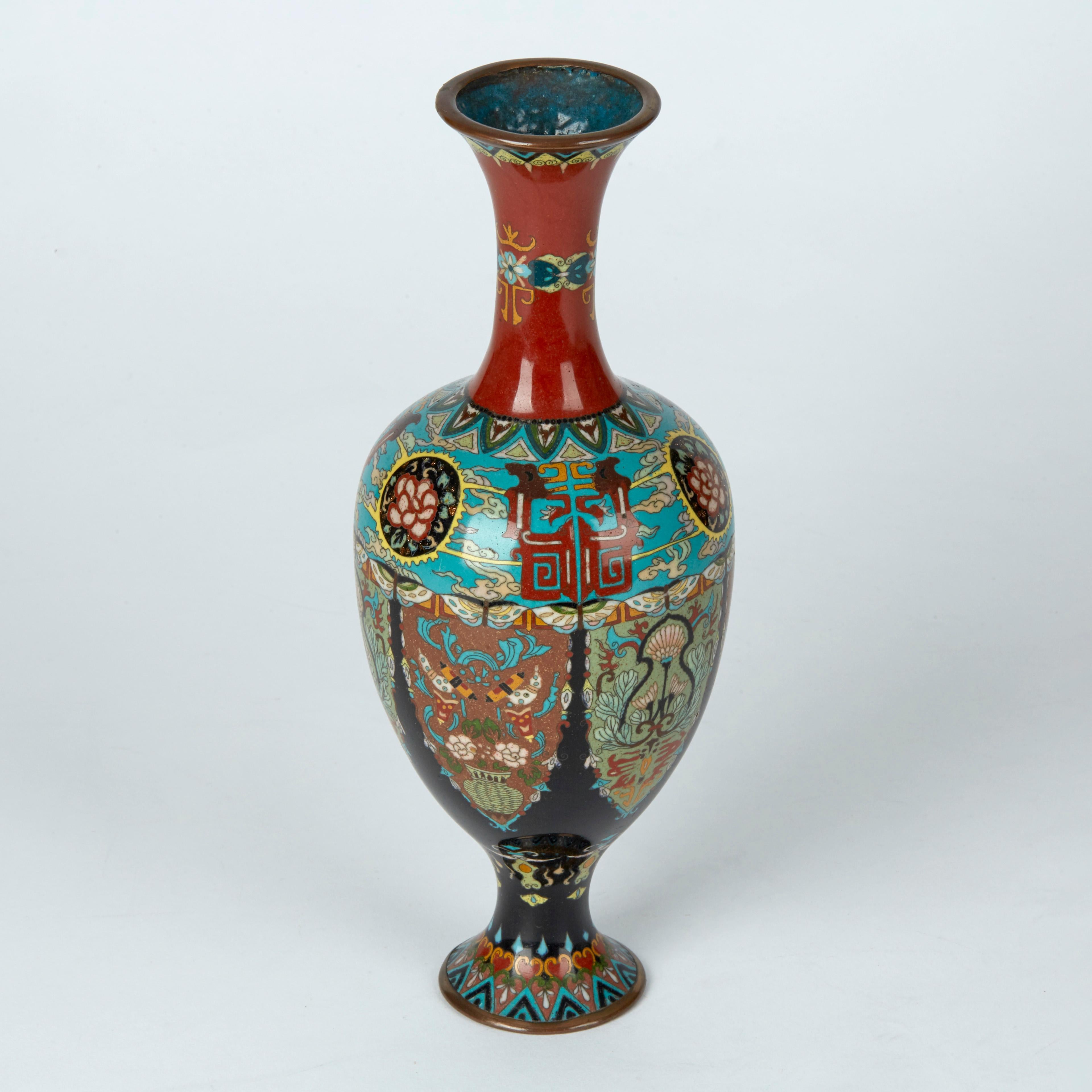 A stunning and elaborately decorated antique Japanese cloisonné vase of elegant shape standing on a narrow rounded pedestal foot with an egg shaped body and tall slender trumpet neck. The vase is decorated with in colored enamels on a blue and red
