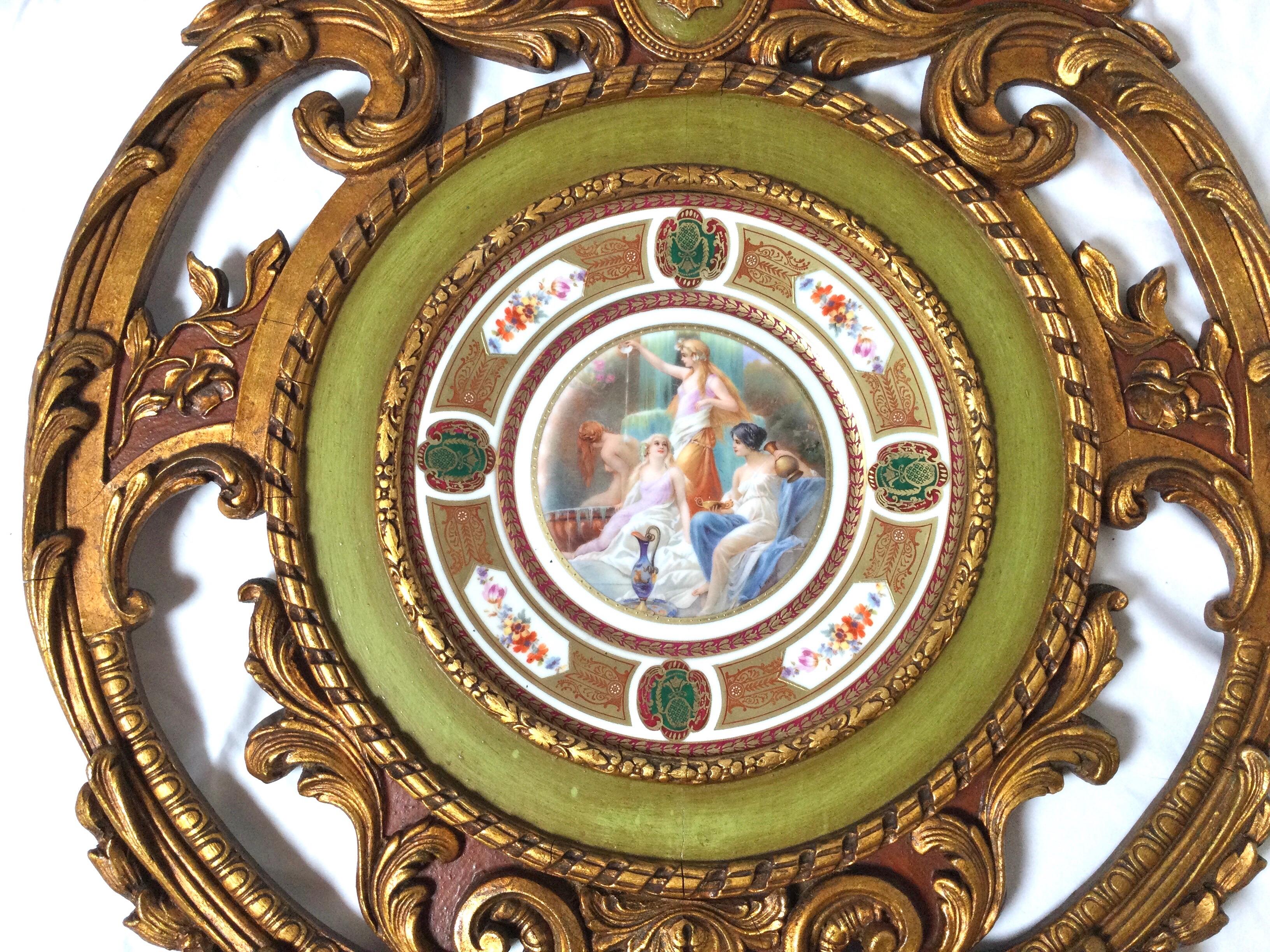 Elegante plato de estilo neoclásico vibrantemente coloreado con elaborado marco de madera dorada y policromada reticulada. Placa con tres doncellas en primer plano y una al fondo bañándose.